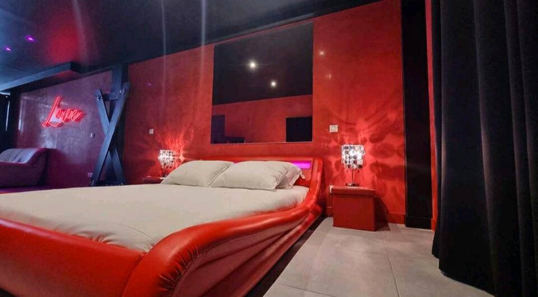 Lit king size design rouge et ambiance tamisée - Appartement balnéo et sauna privés The Red Room