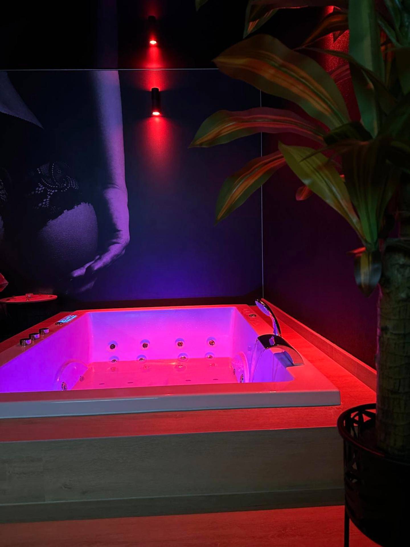 Jacuzzi privatif avec éclairage rose et violet - Love Room Pontarlier - L'Écrin de Saint - Red Room by Loveroomeo