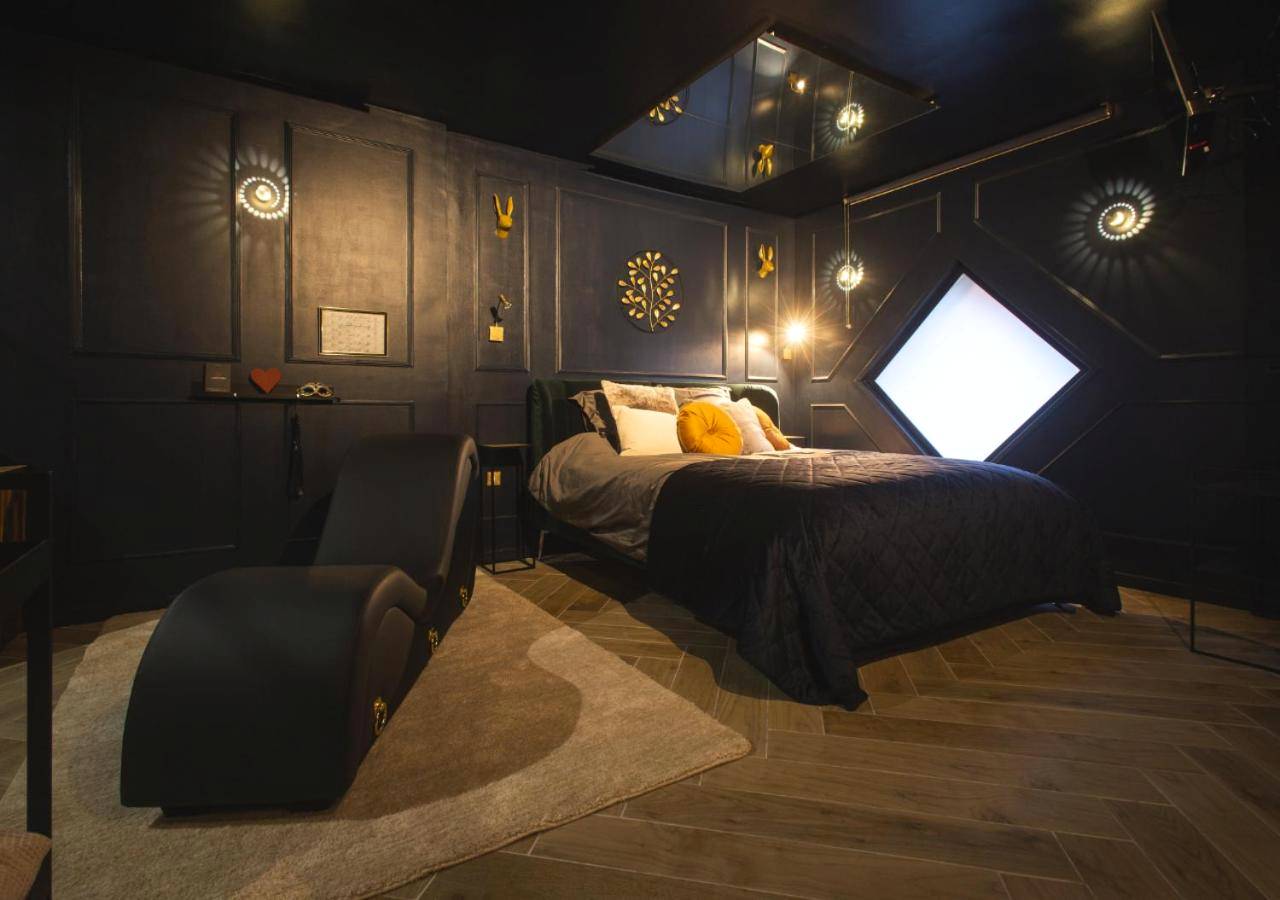 Chambre sombre avec miroir au plafond et sofa - Le Refuge Bleu