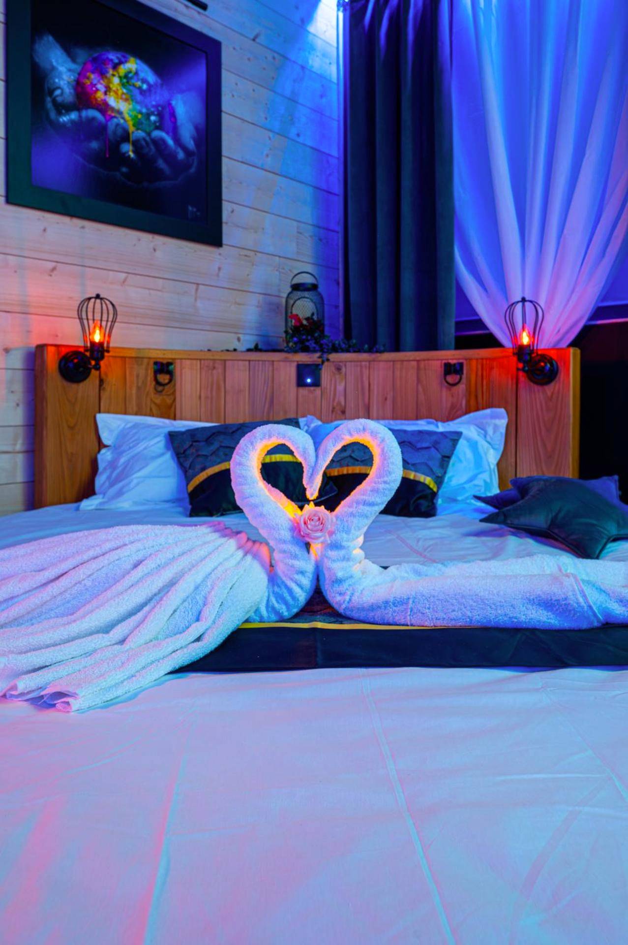 Cygnes en serviettes sur lit avec tête de lit bois - Rien Que Nous