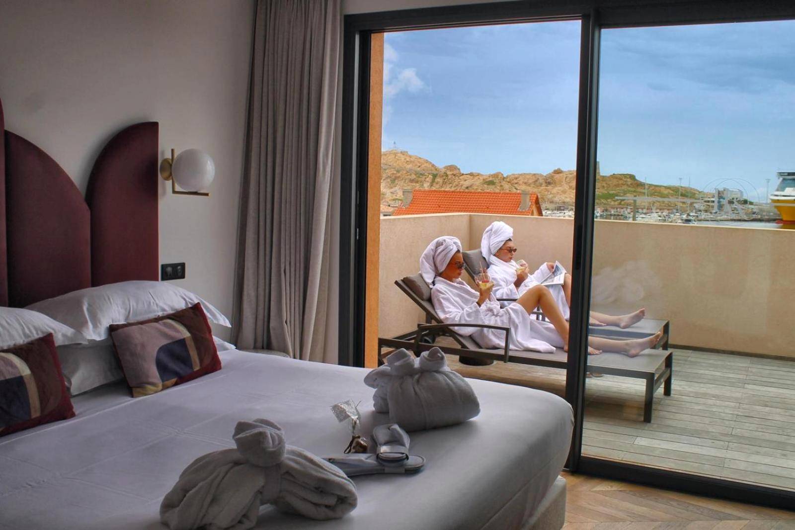 Terrasse avec transats et vue sur le port - Hôtel & Spa Rocabella