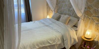 Lit double avec voilages et mur en pierre - Romantica Spa