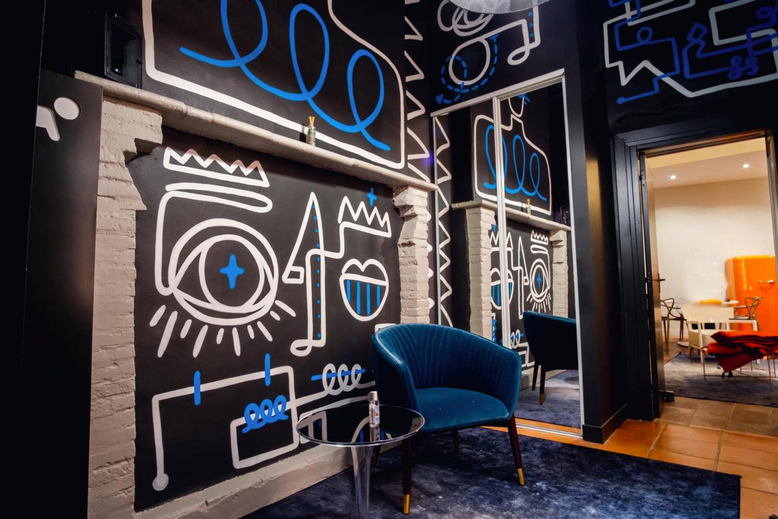 Fauteuil bleu devant un mur au style street art - Love Room Montauban - room five - parking, balnéothérapie, place...