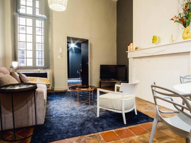 Espace de vie avec tapis bleu et fauteuil blanc - room five - parking, balnéothérapie, place nationale, un havre de paix