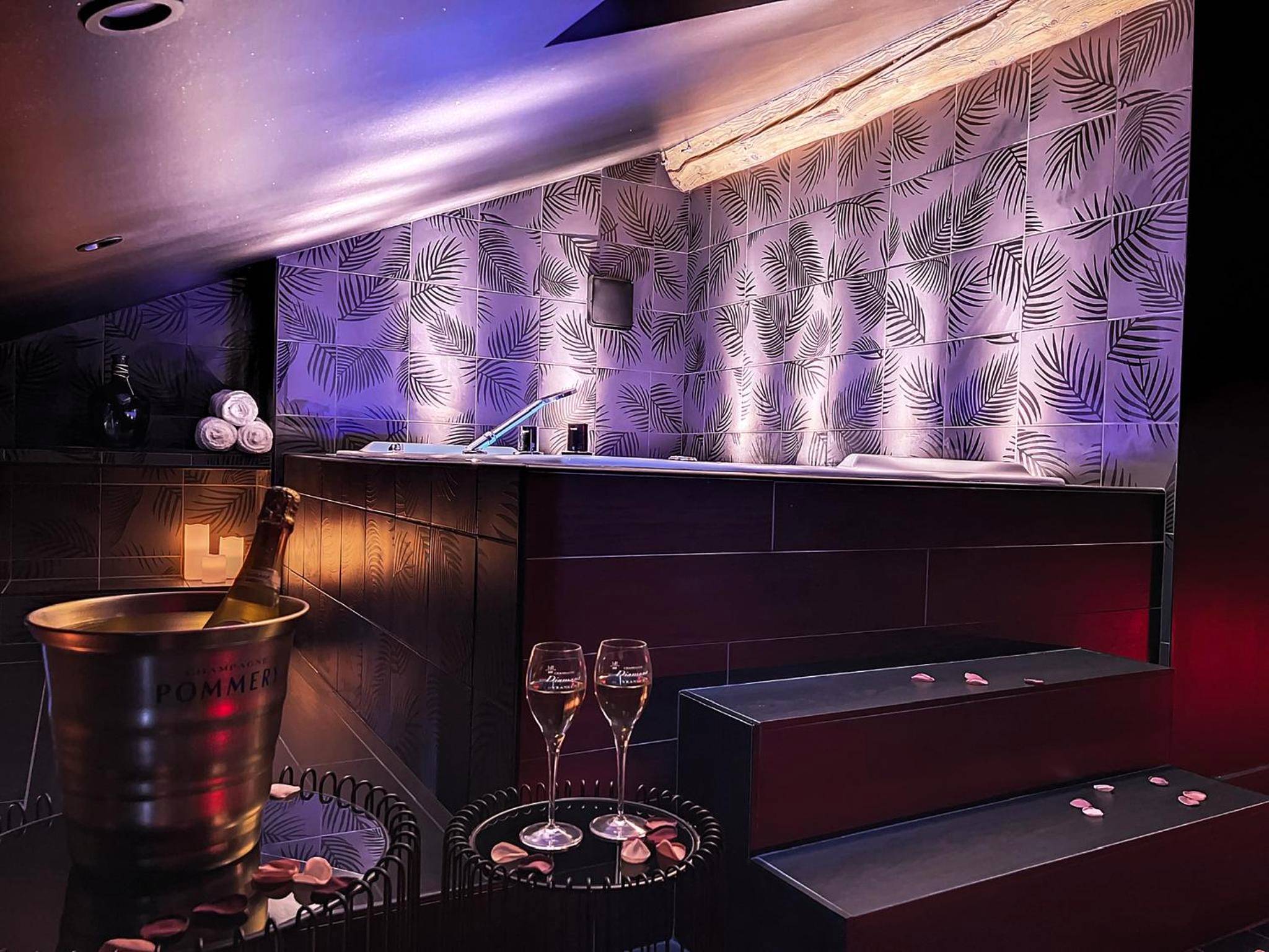 Champagne et flûtes devant le jacuzzi éclairé - Suite Rouge baiser avec Jacuzzi privatif - LoveRoom Insolite
