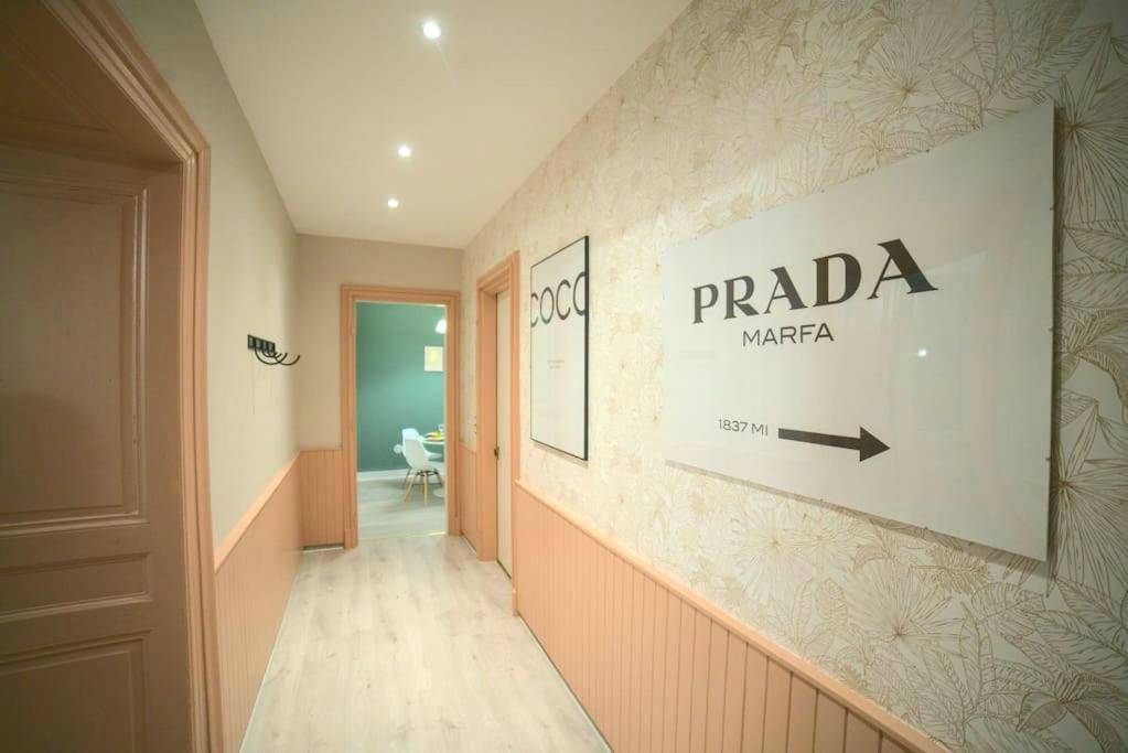 Couloir décoré avec cadres Prada et Coco - Suite Élégante Centre - Royal Room jacuzzi haut de gamme centre ville