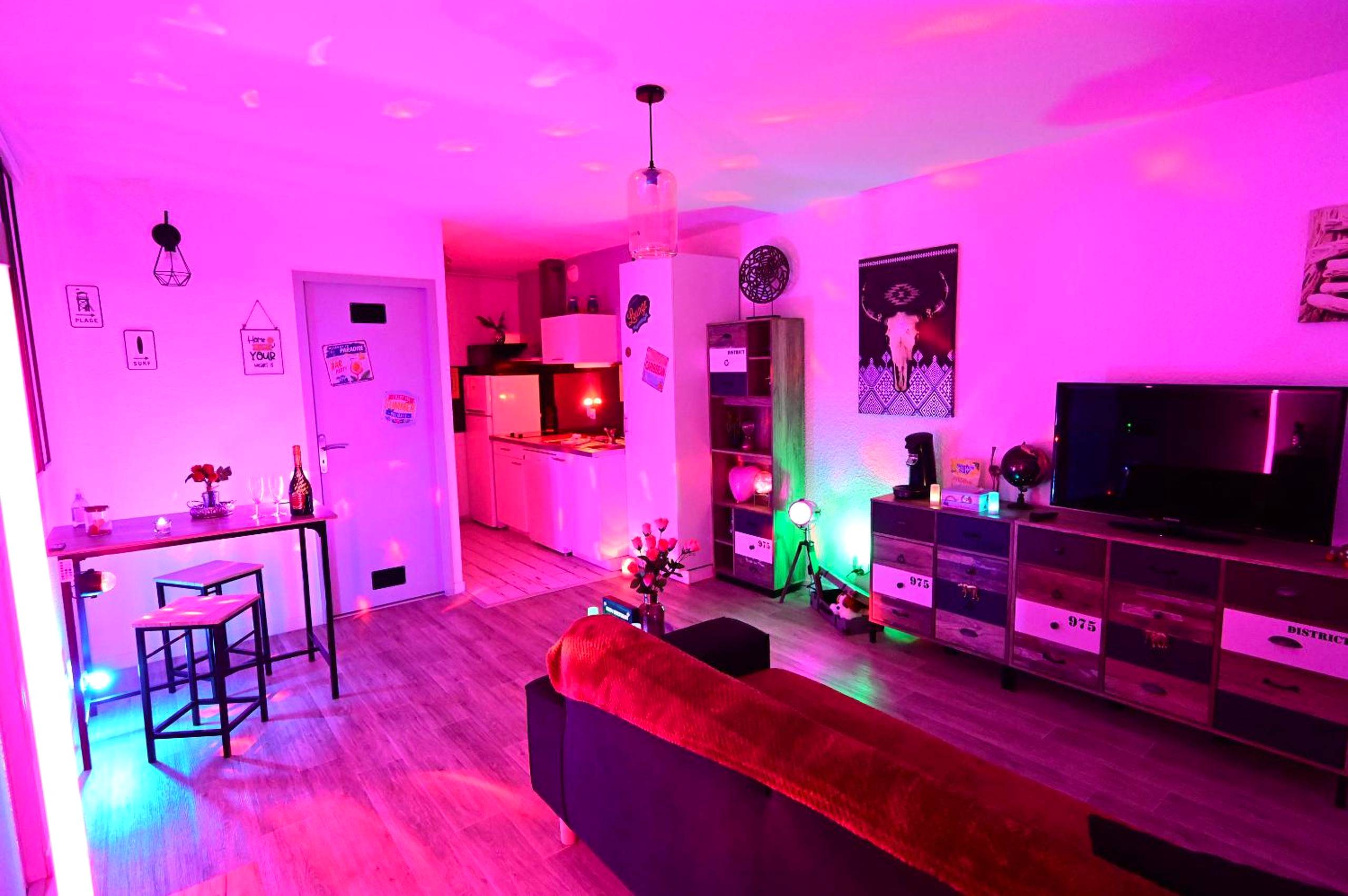 Salon et cuisine ouverte avec lumières roses - Luxe Sauna Privatif et Grand bain Jacuzzi à deux à Biscarosse Plage pour...