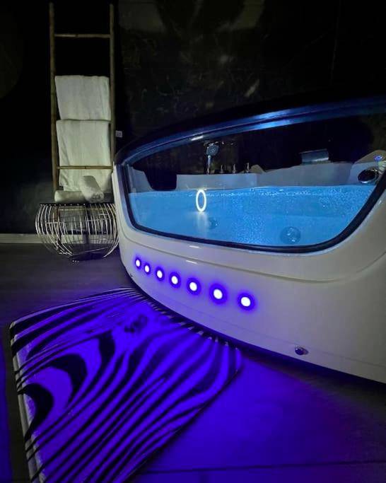 Jacuzzi avec paroi vitrée et éclairage LED bleu - Love Room Montagnac - la savane room