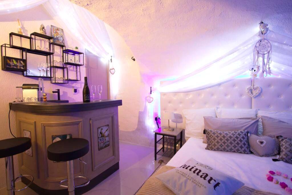 Espace bar avec tabourets et lit en arrière - plan - Les Secrets d'Alcôve, nuits Romantiques avec SPA