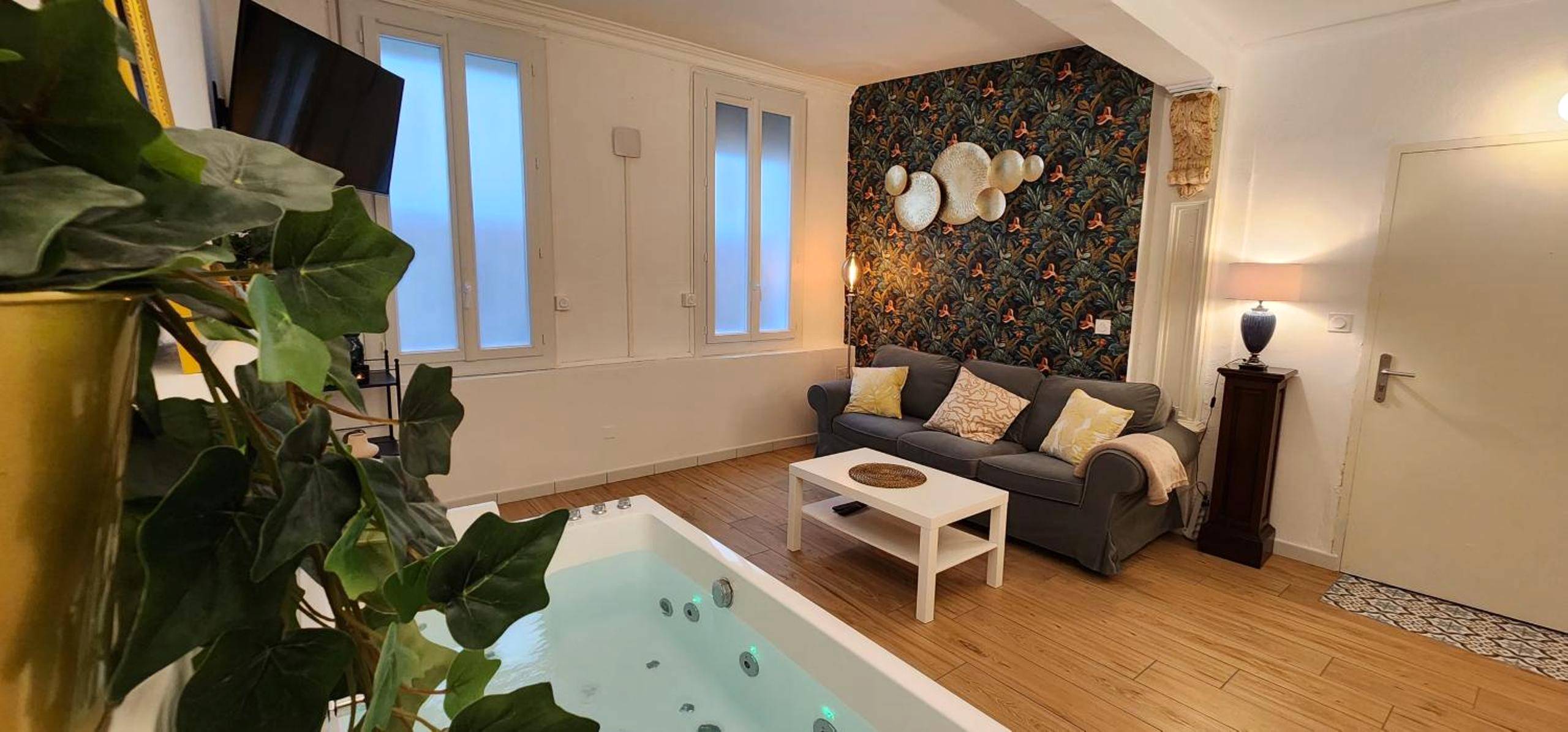 Salon avec jacuzzi privatif et mur décoratif - Sérénité au Palais Suite romantique Jacuzzi