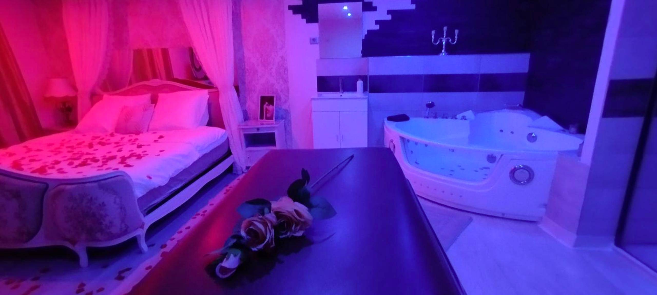 Lit avec pétales et jacuzzi sous lumière rose - Love Room Saint - Amarin - Love room avec spa privatif