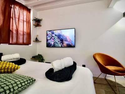 Écran plat mural face au lit et fauteuil design - Le Spa Beauvoisine - Jacuzzi Sauna Rouen centre Free parking