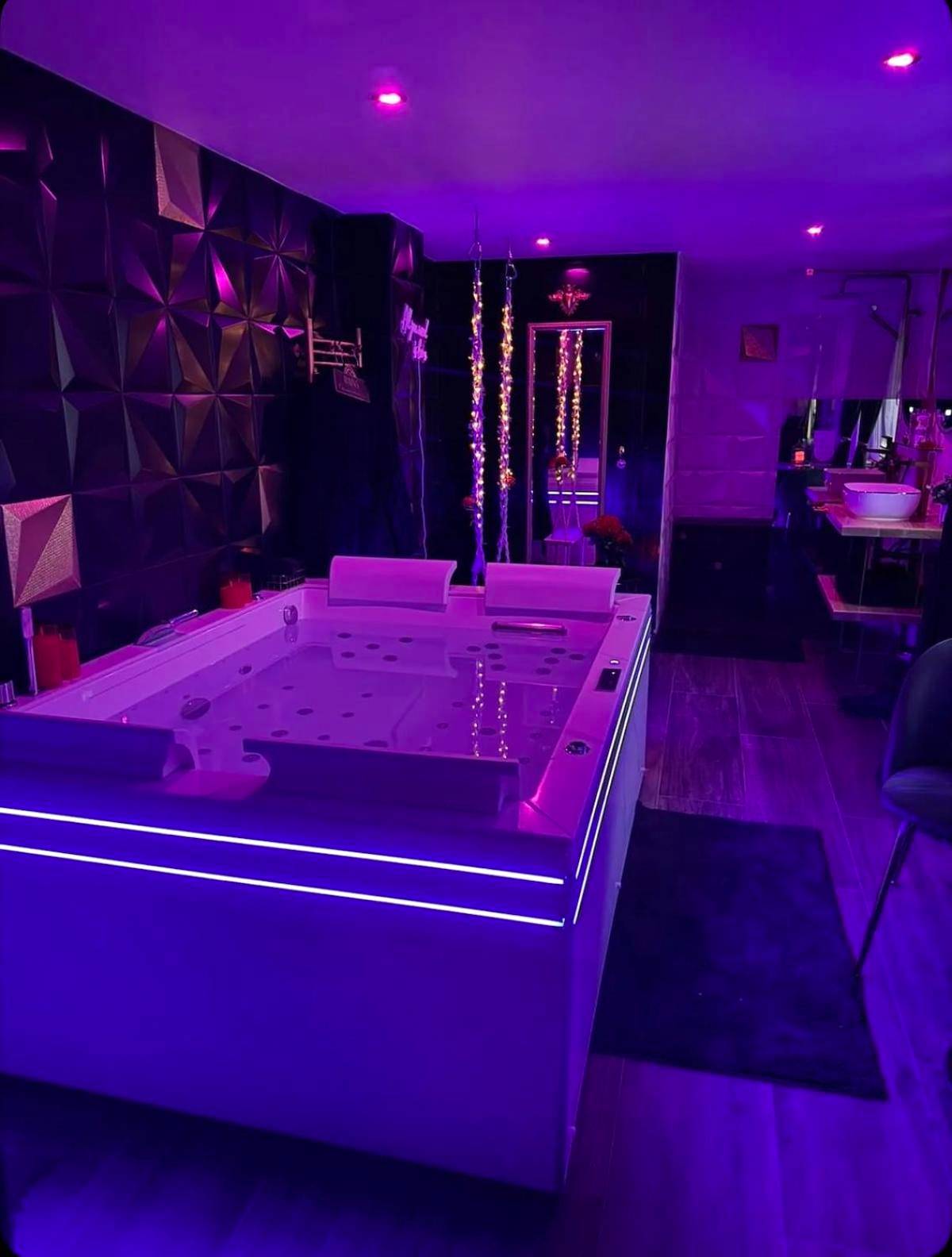 Jacuzzi privatif avec éclairage LED violet - Love Room élégante spa privatif et extérieur cosy