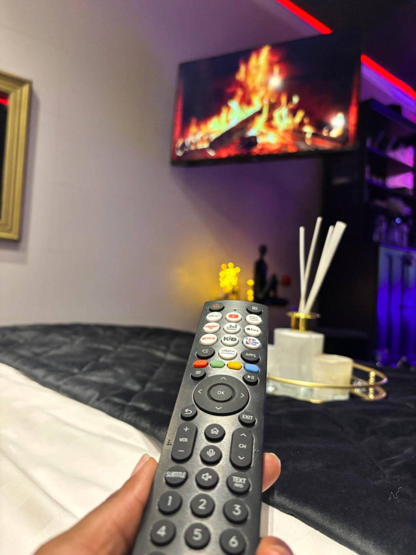 Télécommande devant écran TV effet cheminée - Love Room élégante spa privatif et extérieur cosy
