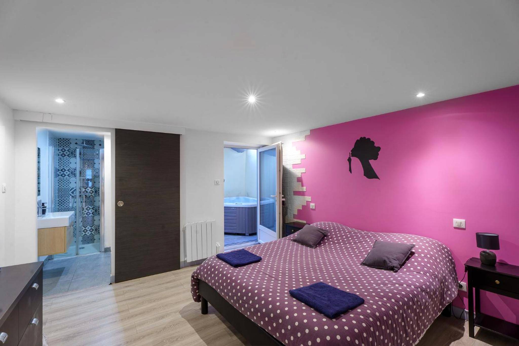 Chambre avec lit double et mur rose décoré - Appartement spa privatif et cinéma centre ville