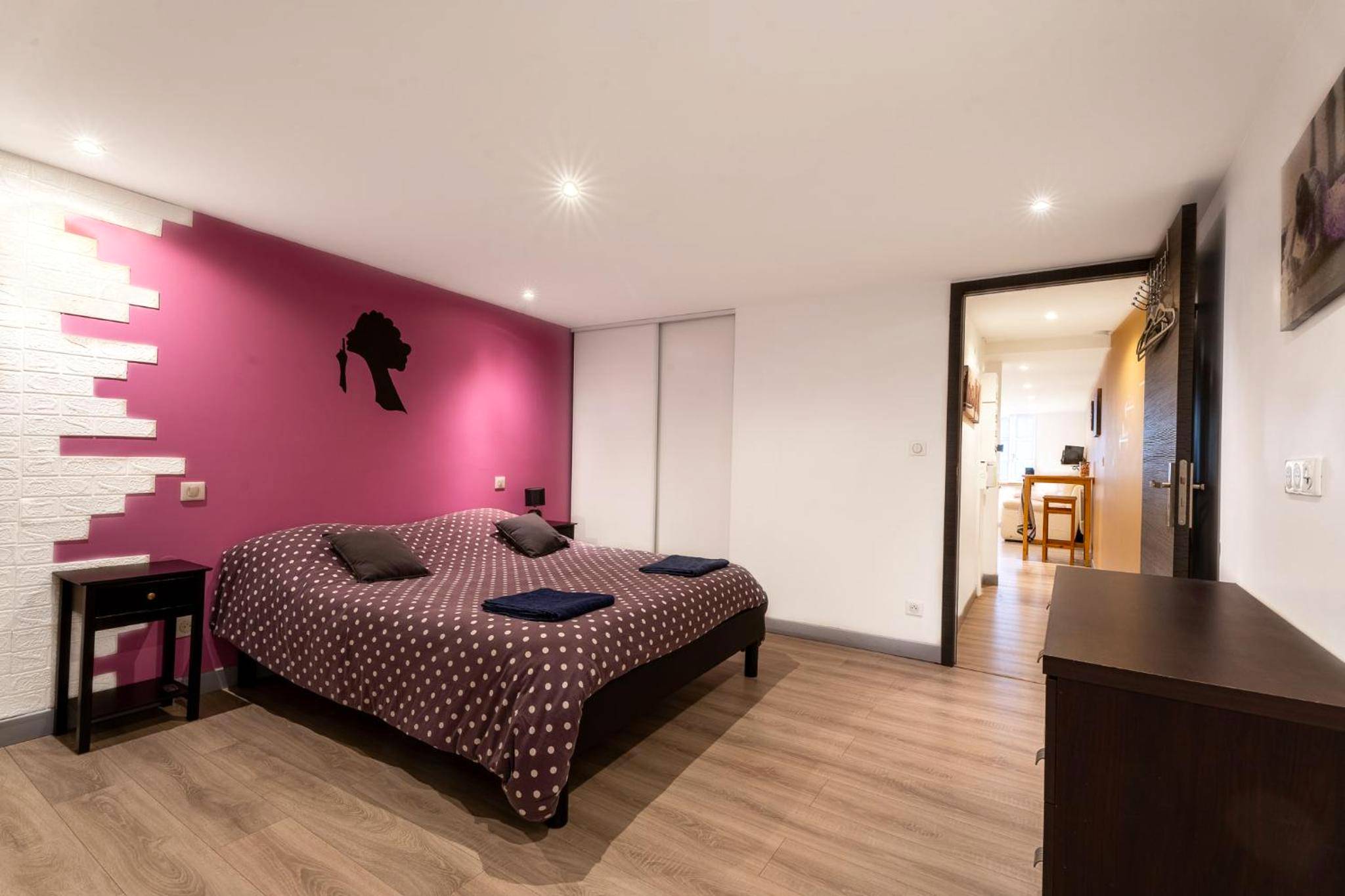 Lit double face à une commode en bois - Appartement spa privatif et cinéma centre ville