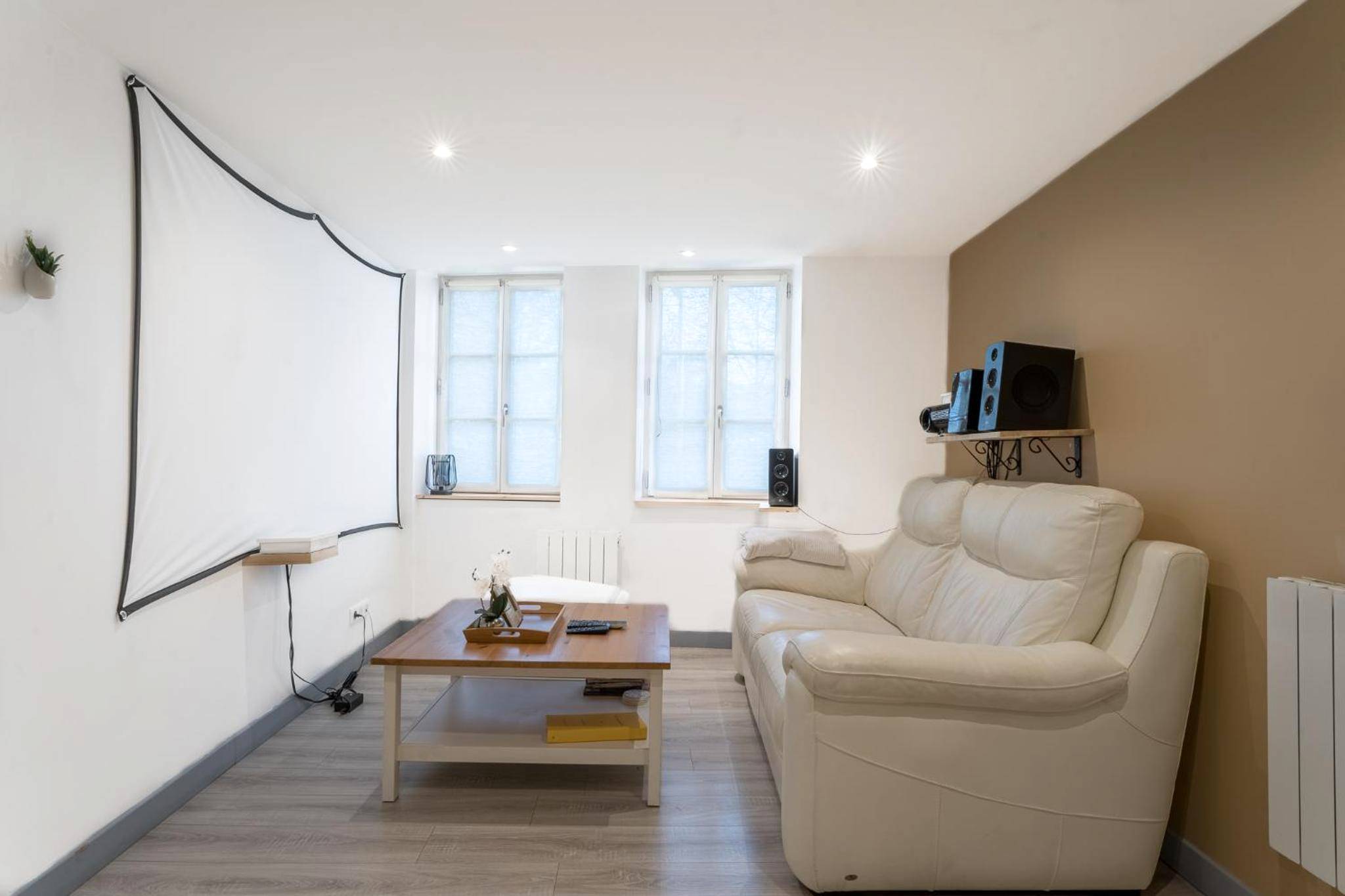 Salon avec canapé en cuir et écran de projection - Appartement spa privatif et cinéma centre ville