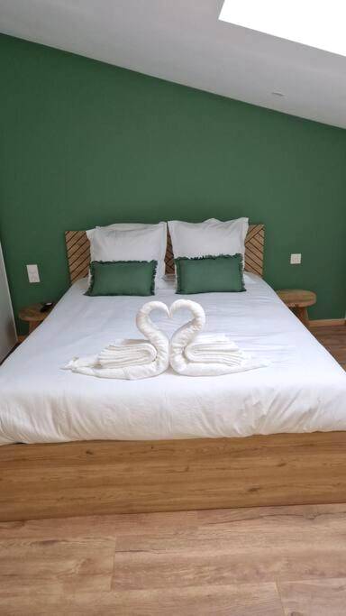 Cygnes en serviettes sur lit et mur vert - Spa des ducs loft 1