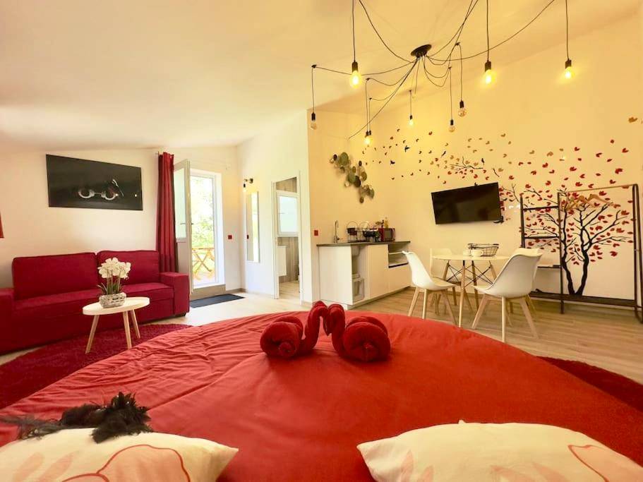 Espace de vie avec lit rond et canapé rouge - SPA JACUZZI et table massage