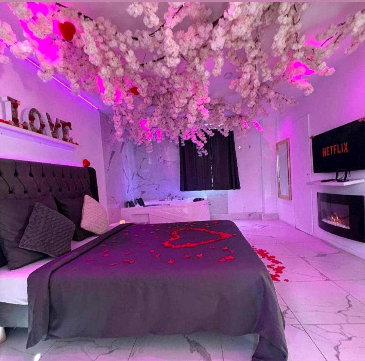 Lit avec pétales de rose et plafond fleuri - Love Room Montmorency - Love Room Appartement Spa Jacuzzi et Terrasse