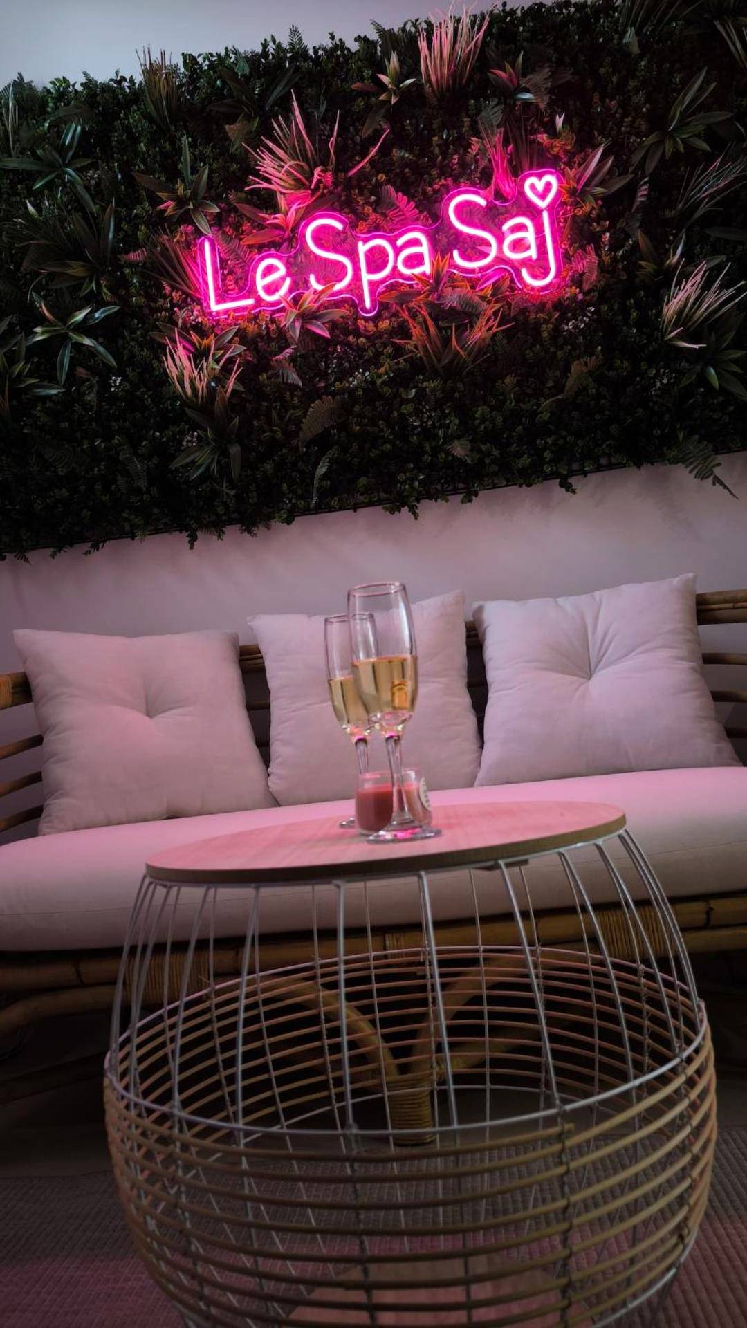 Salon avec néon rose et coupes de champagne - Love Room Frénouville - Le Spa SAJ