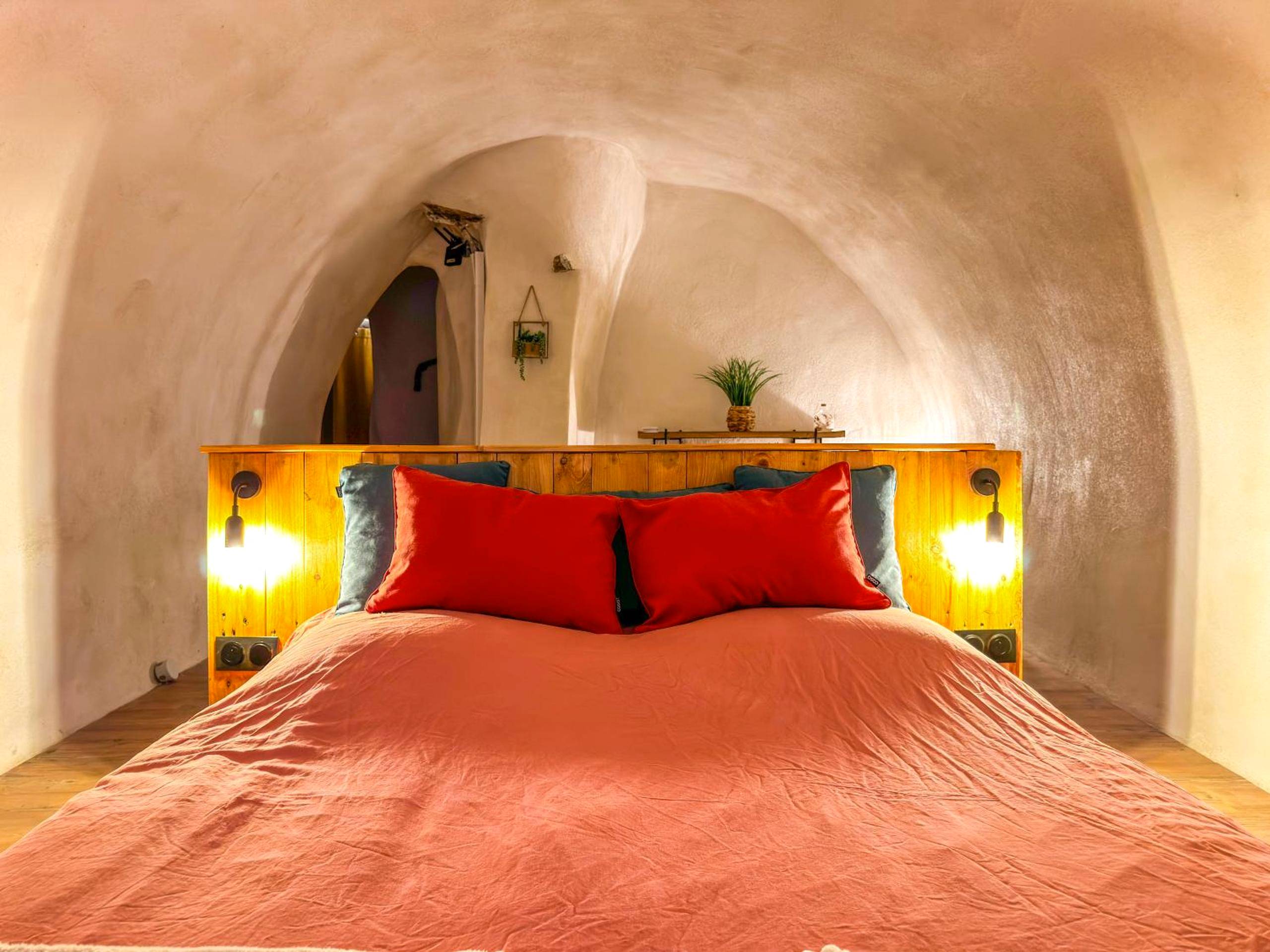 Lit double sous voûte en pierre avec oreillers rouges - Intimiste retraite de Sainte - Logement entier Le Spa des Voutes...