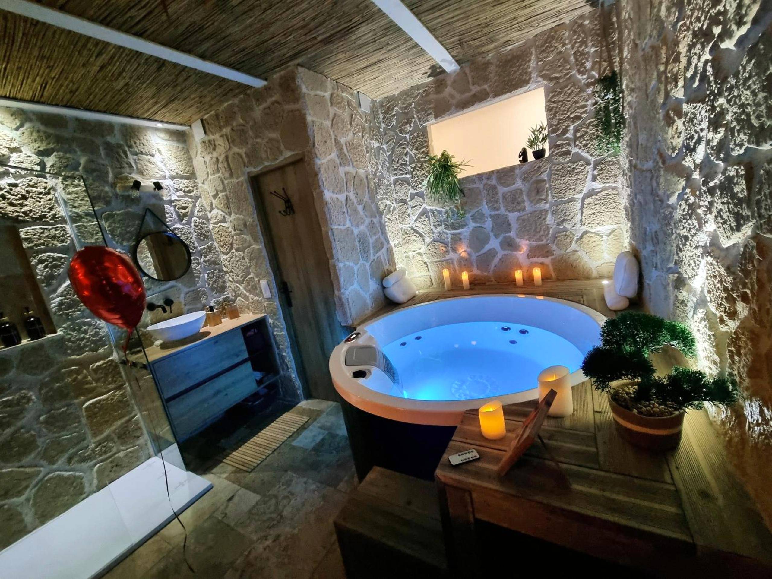 Jacuzzi rond éclairé et mur en pierres - Love Room Le Grau - du - Roi - Les Spas de la mer, Suite & Spa, Love room,...