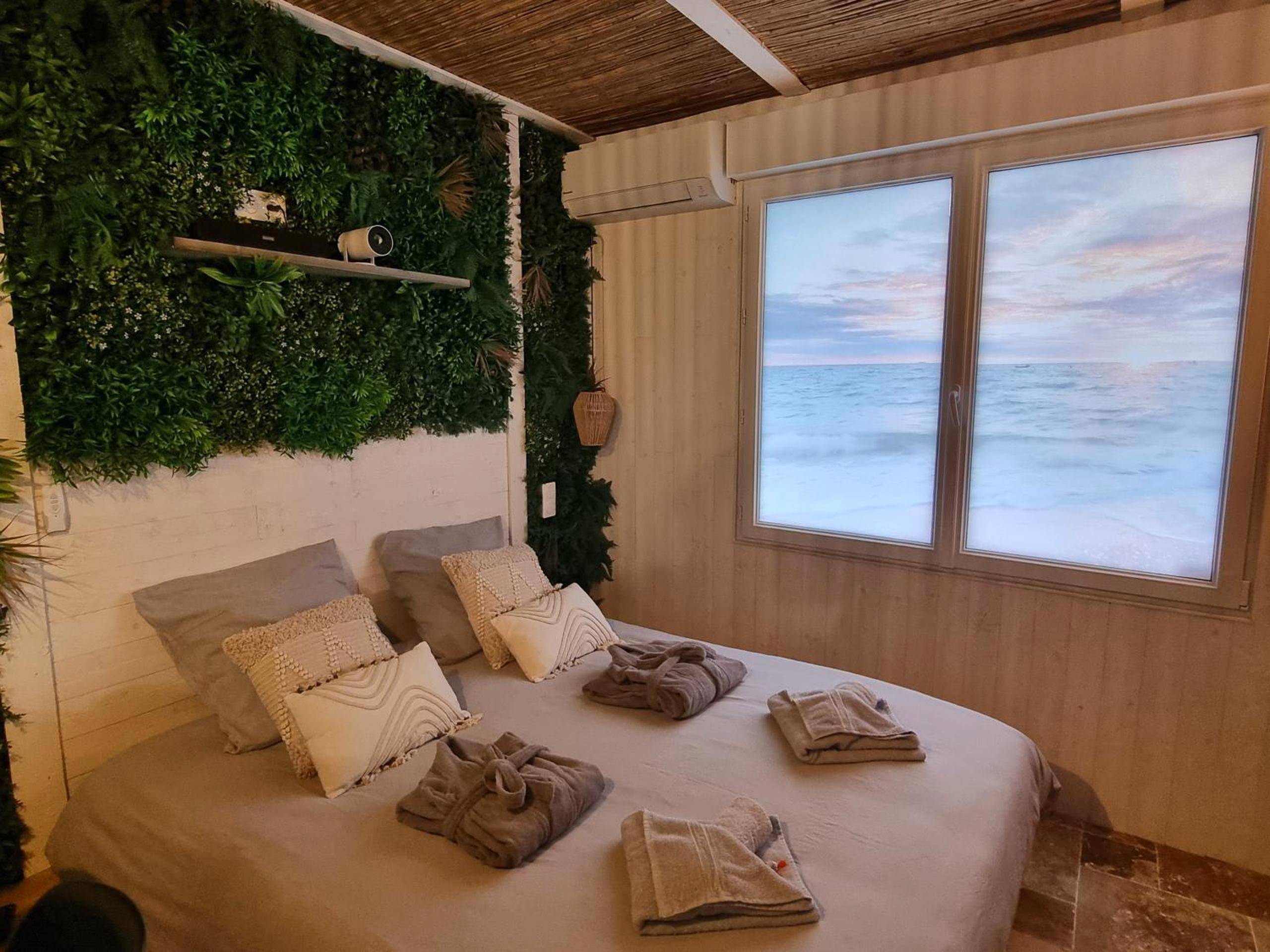 Lit double avec peignoirs et mur végétal - Les Spas de la mer, Suite & Spa, Love room, Plein Cœur du Grau