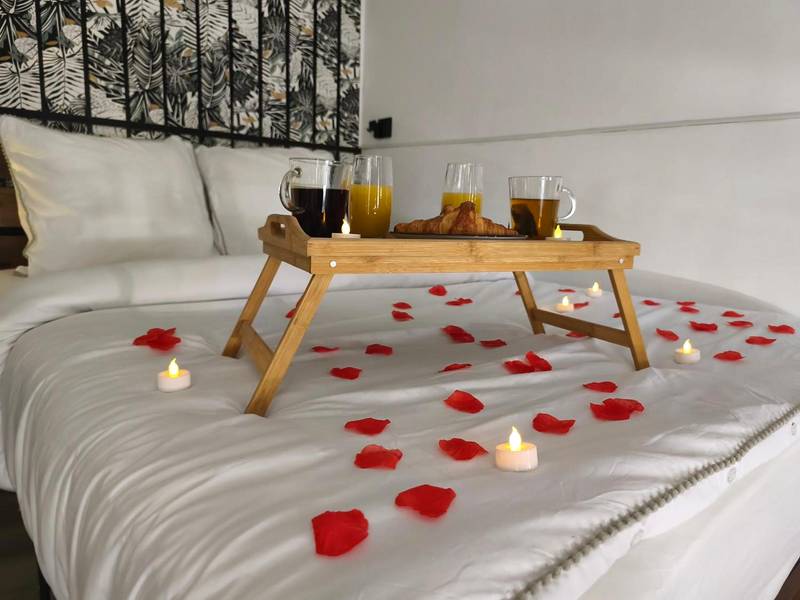 Pétales de roses et bougies sur lit blanc - Studio & Balnéo privatif