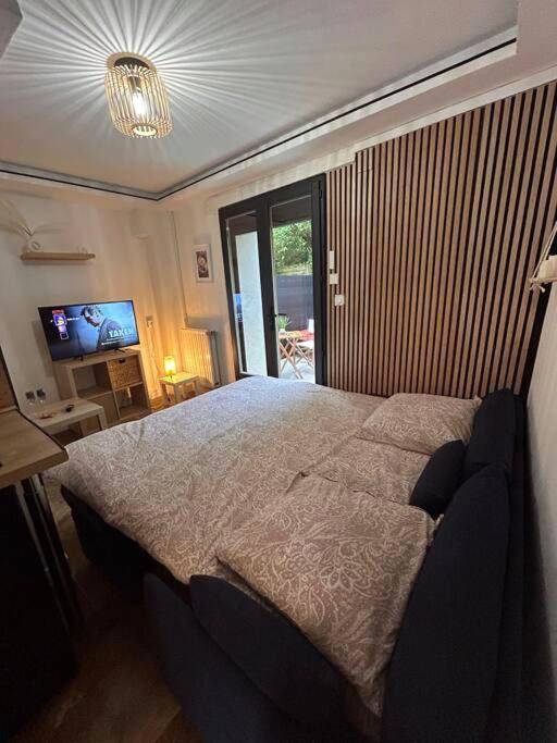 Lit double avec mur en tasseaux de bois - Petit studio et son spa abrité