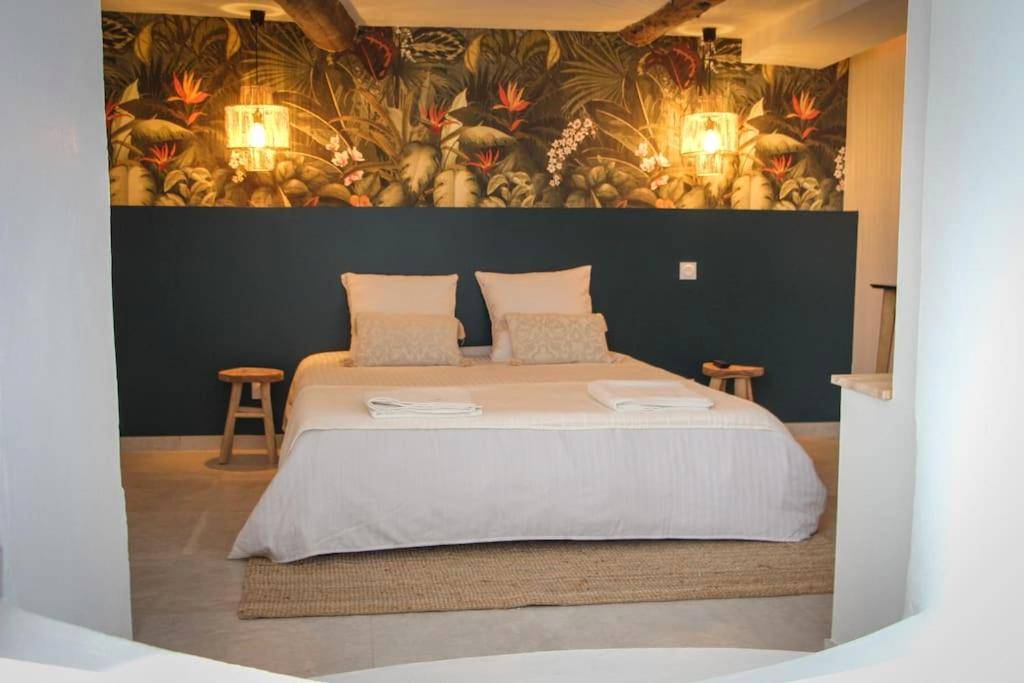 Lit double devant un mur au décor tropical - Suite Luxueuse Jacuzzi SUITE AMANTIS By Noma