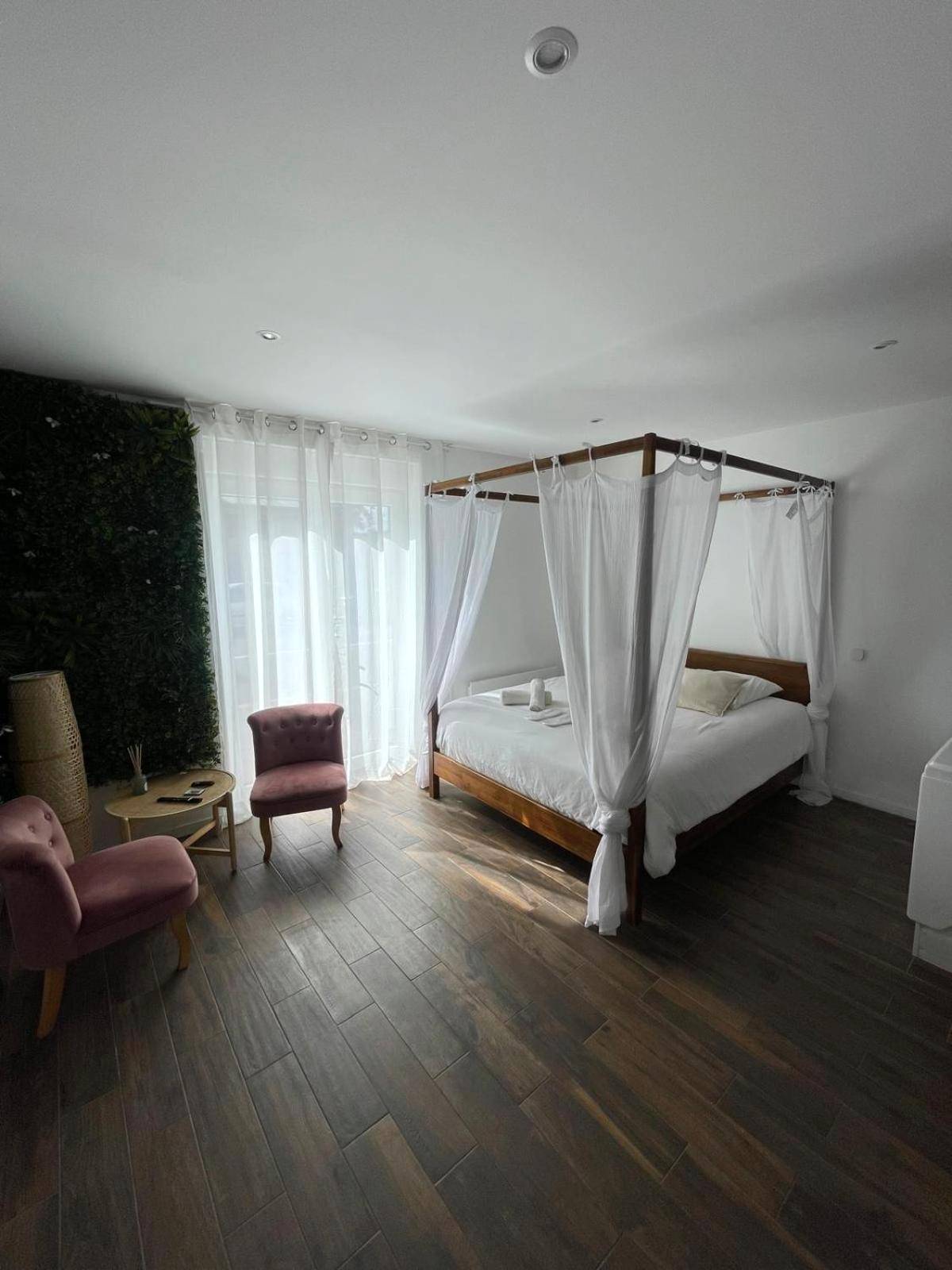 Lit à baldaquin et fauteuils en velours rose - La Suite Bali Jacuzzi,Sauna,Netflix,Disney