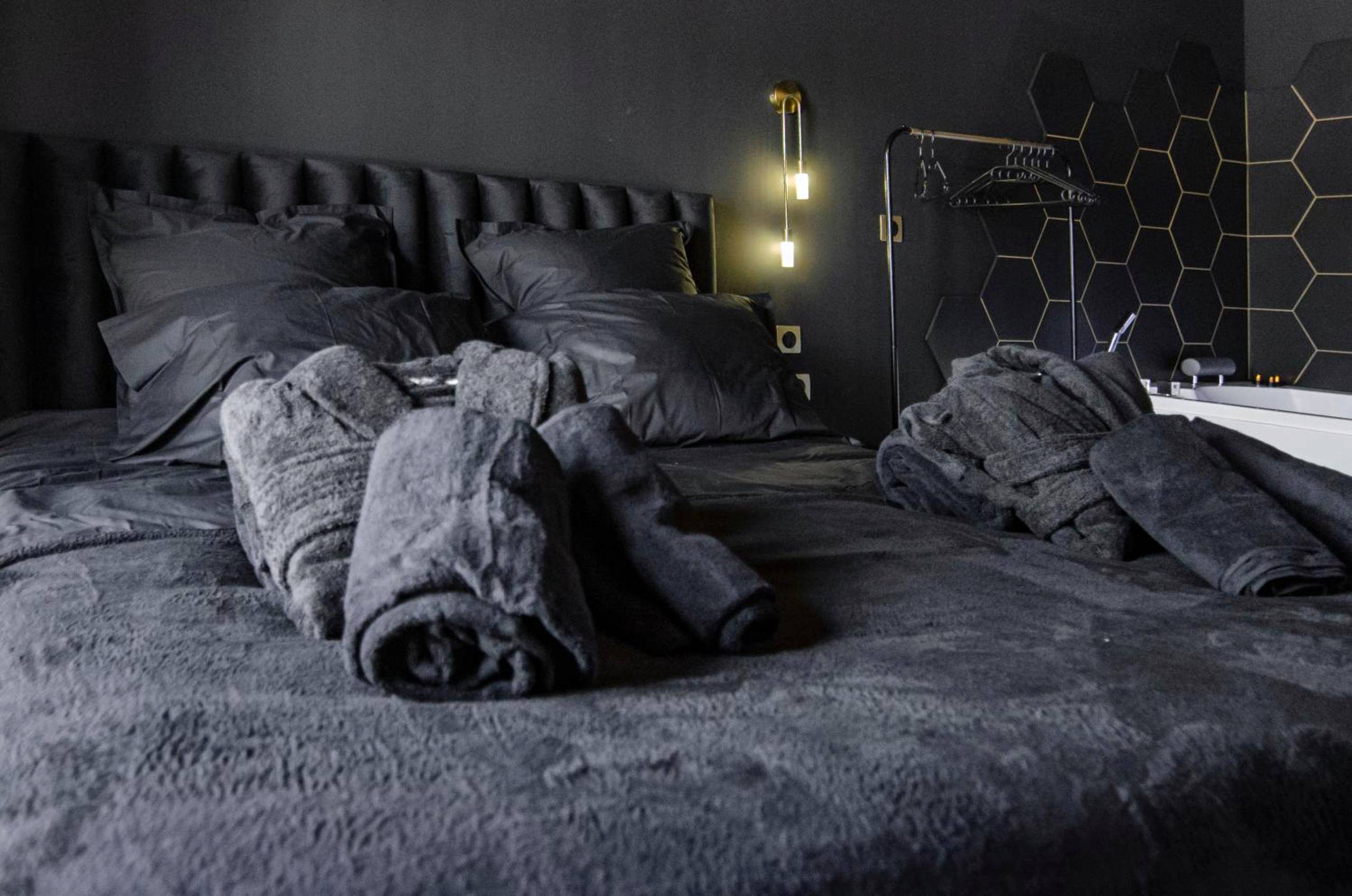 Peignoirs et serviettes posés sur lit sombre - Suite Balneo Hammam Noire et Or