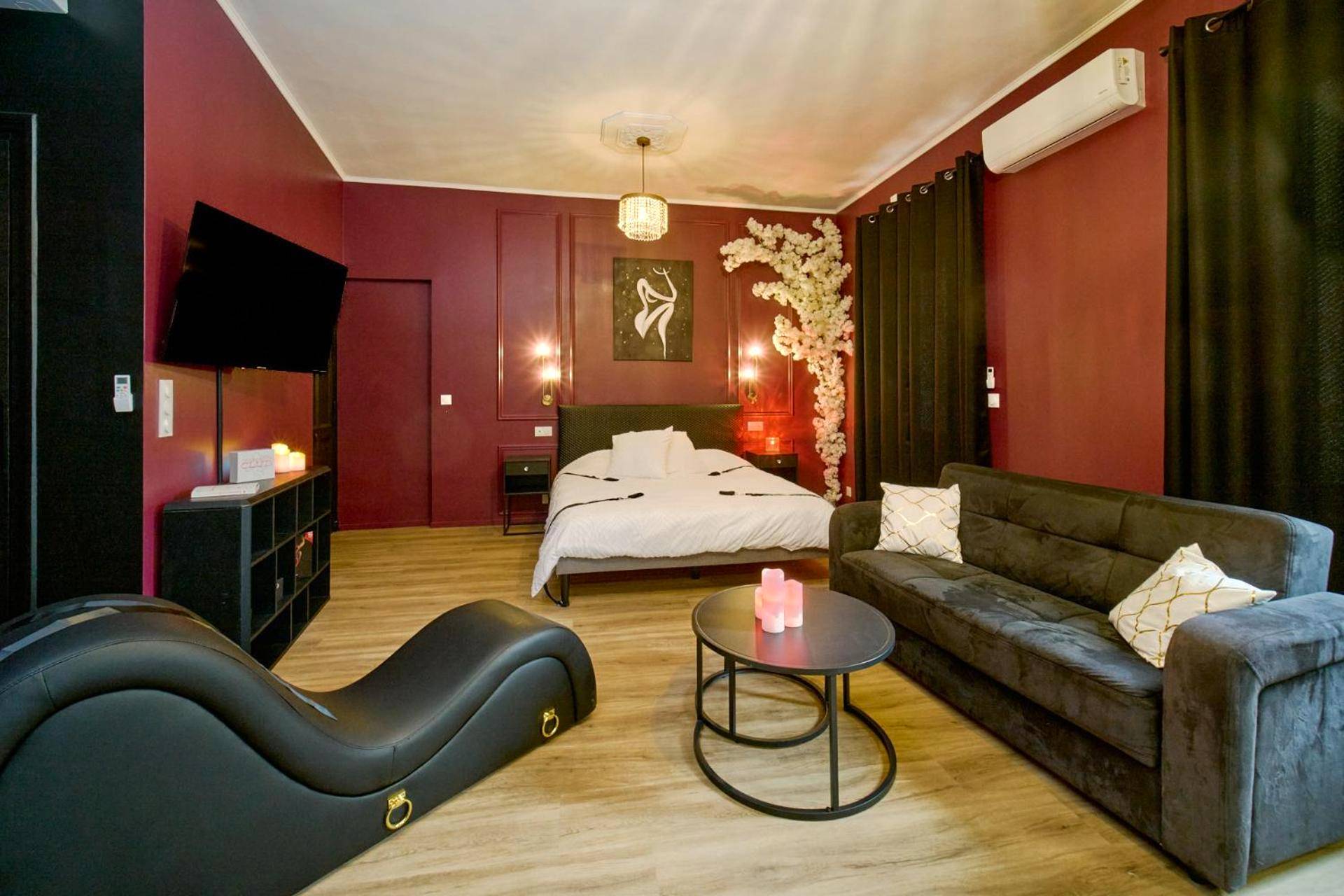 Salon avec sofa tantra et lit en arrière - plan - Suite romantique avec Balneo et jeux coquins