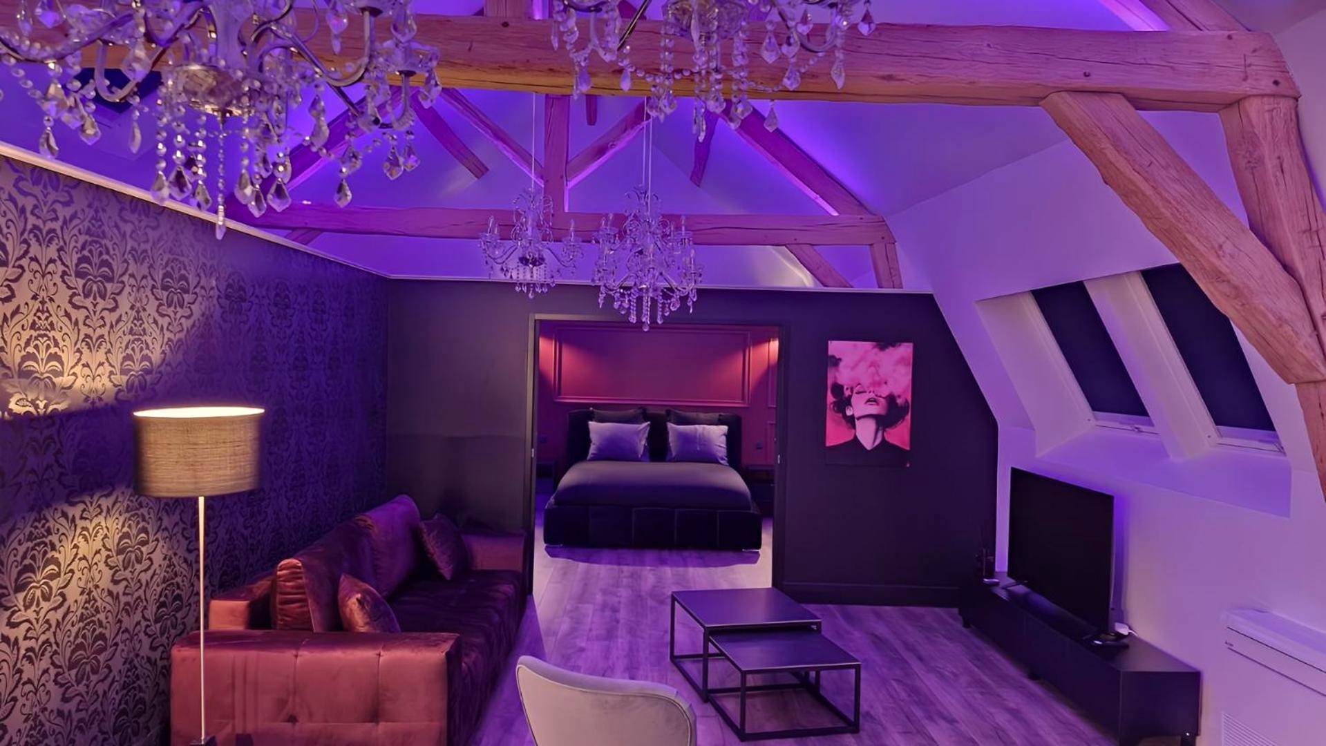 Salon avec canapé velours et éclairage violet - Love Room Boissettes - La suite Baroque jacuzzi au cœur du château de...