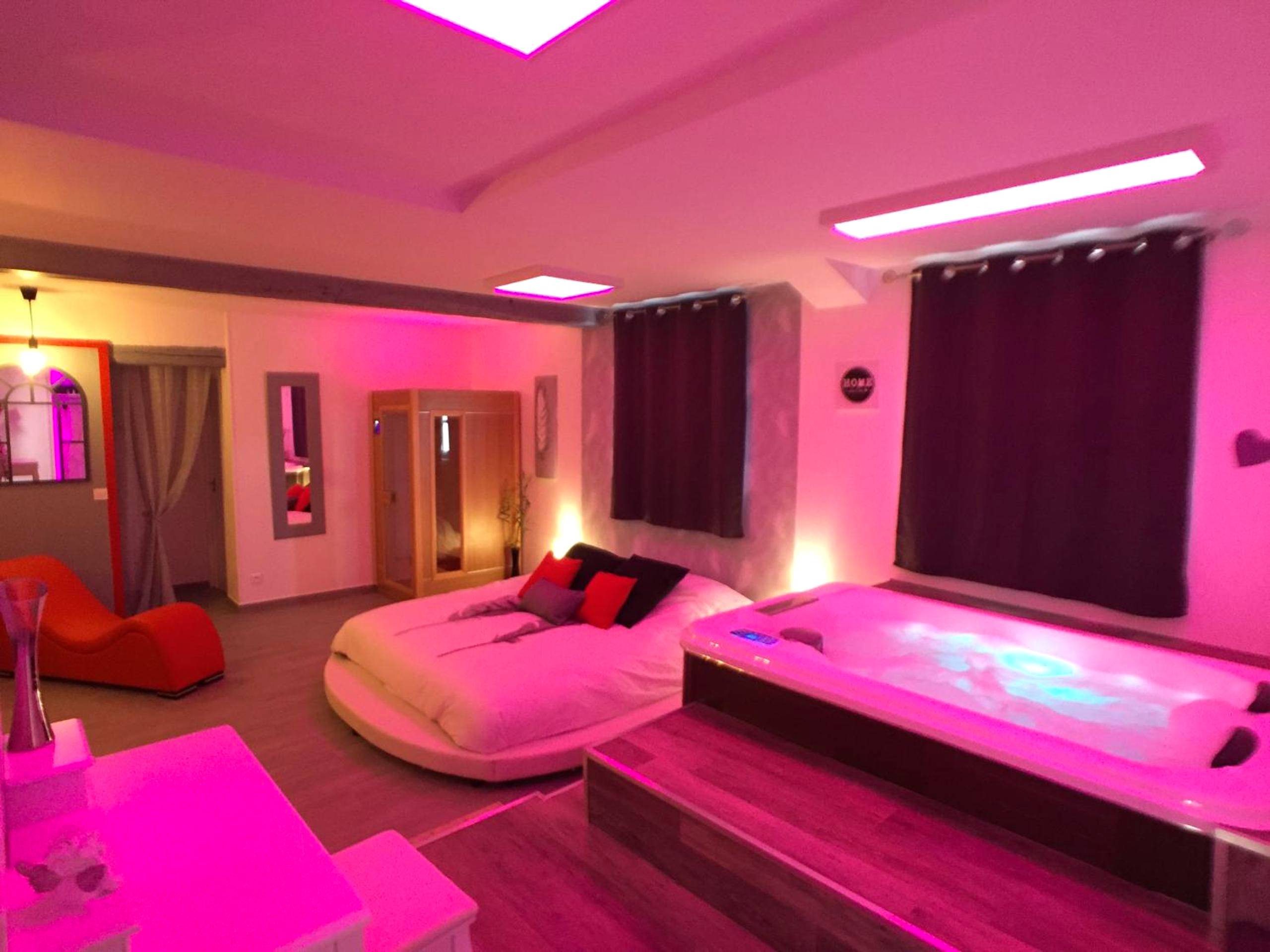 Suite avec lit rond et jacuzzi sous néons roses - Love Room Moisenay - Suite Cupidon - Domaine des trois châteaux