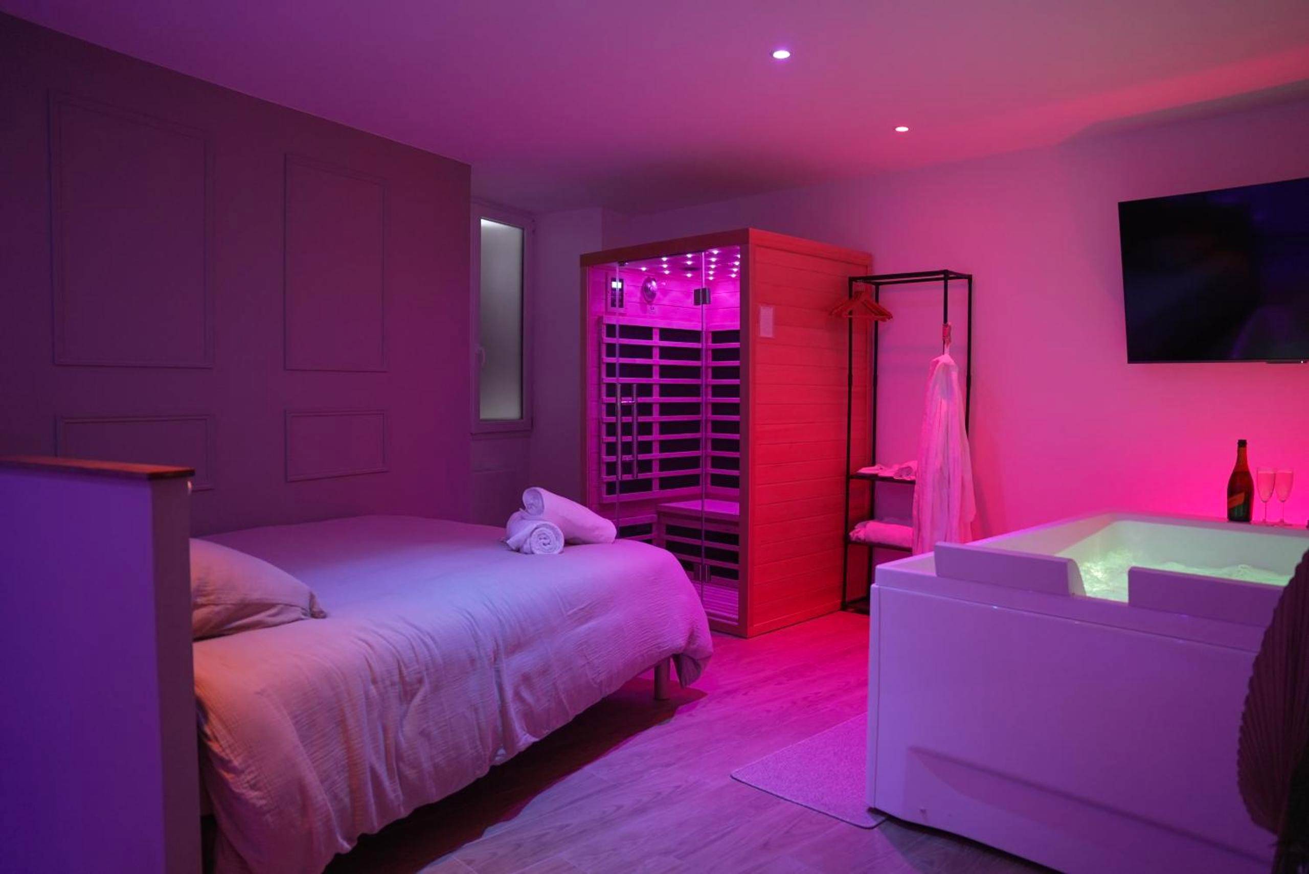Lit double face au jacuzzi sous lumière rose - Suite Détente - Spa & Sauna