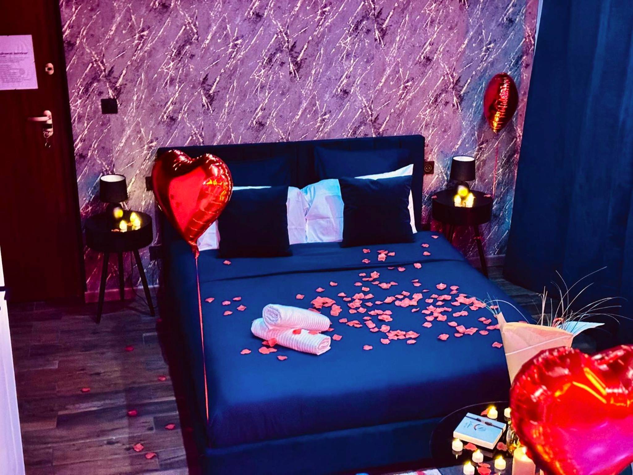 Lit décoré de pétales et ballons en cœur - La Suite Élixir & Spa