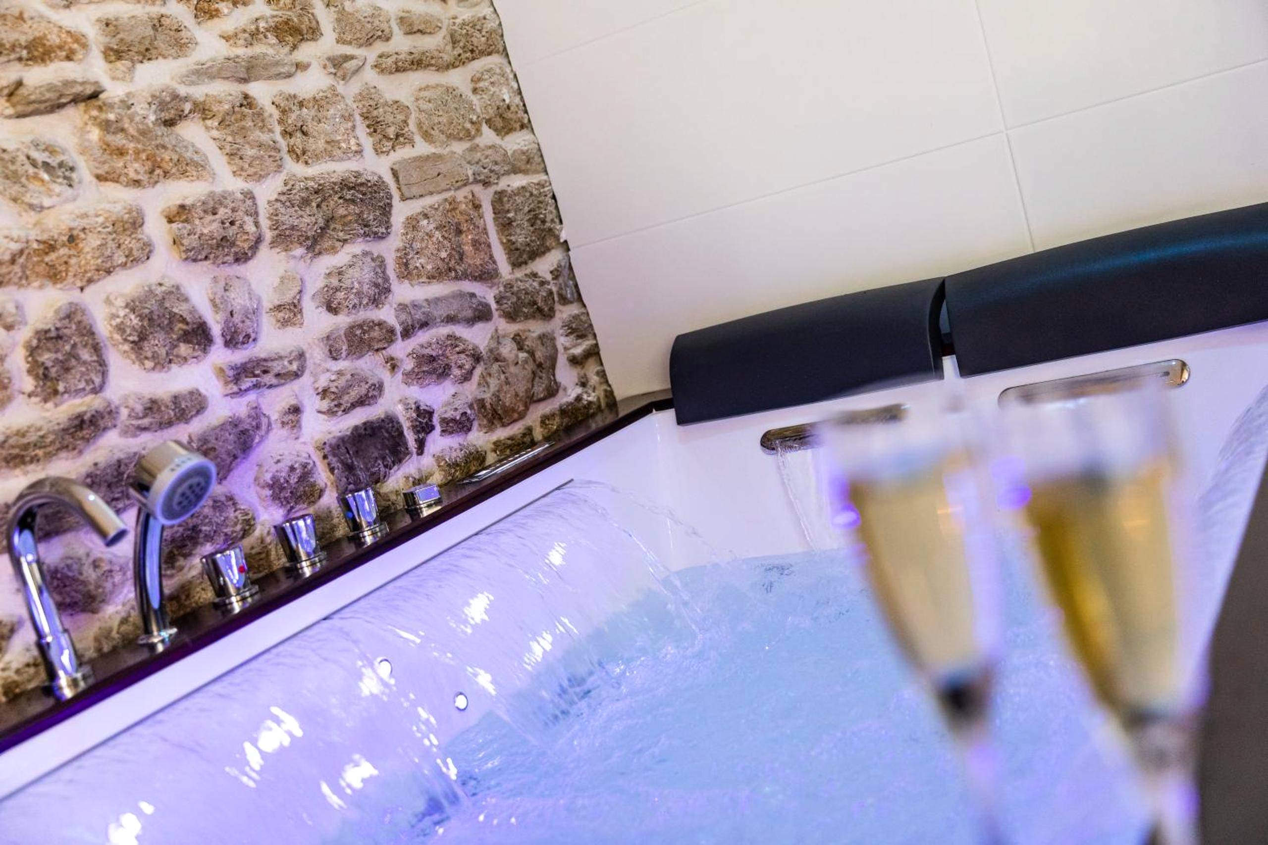 Baignoire balnéo et mur en pierres apparentes - Love Room Longmesnil - La Suite de l'Etoile