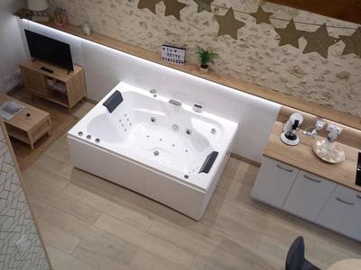 Baignoire balnéo blanche sous mur en pierre - Love Room Courgains - La Suite Etoilée - Balnéo privative