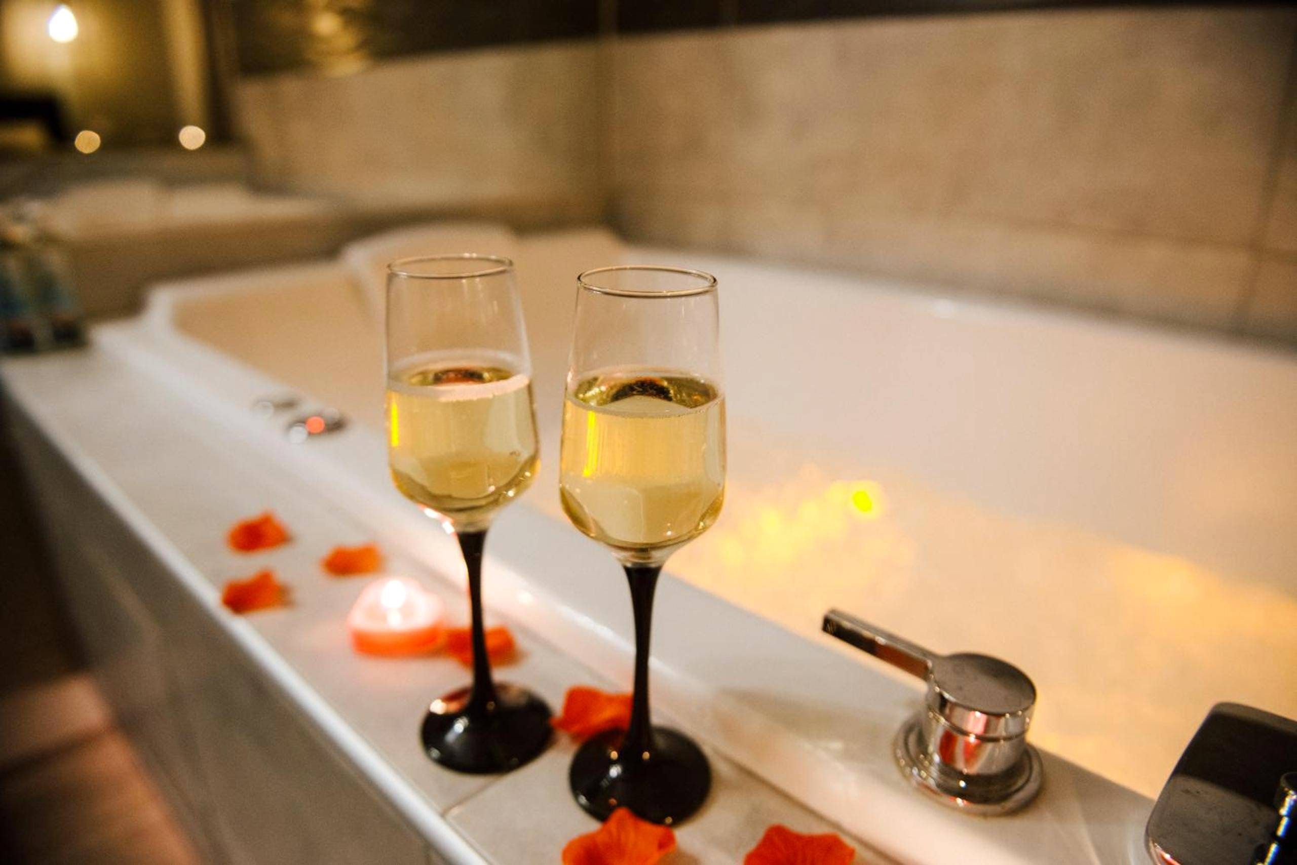 Coupes de champagne au bord d'une baignoire - Love Room Perpignan - La Suite Romantique avec Jacuzzi au Cœur de Perpignan