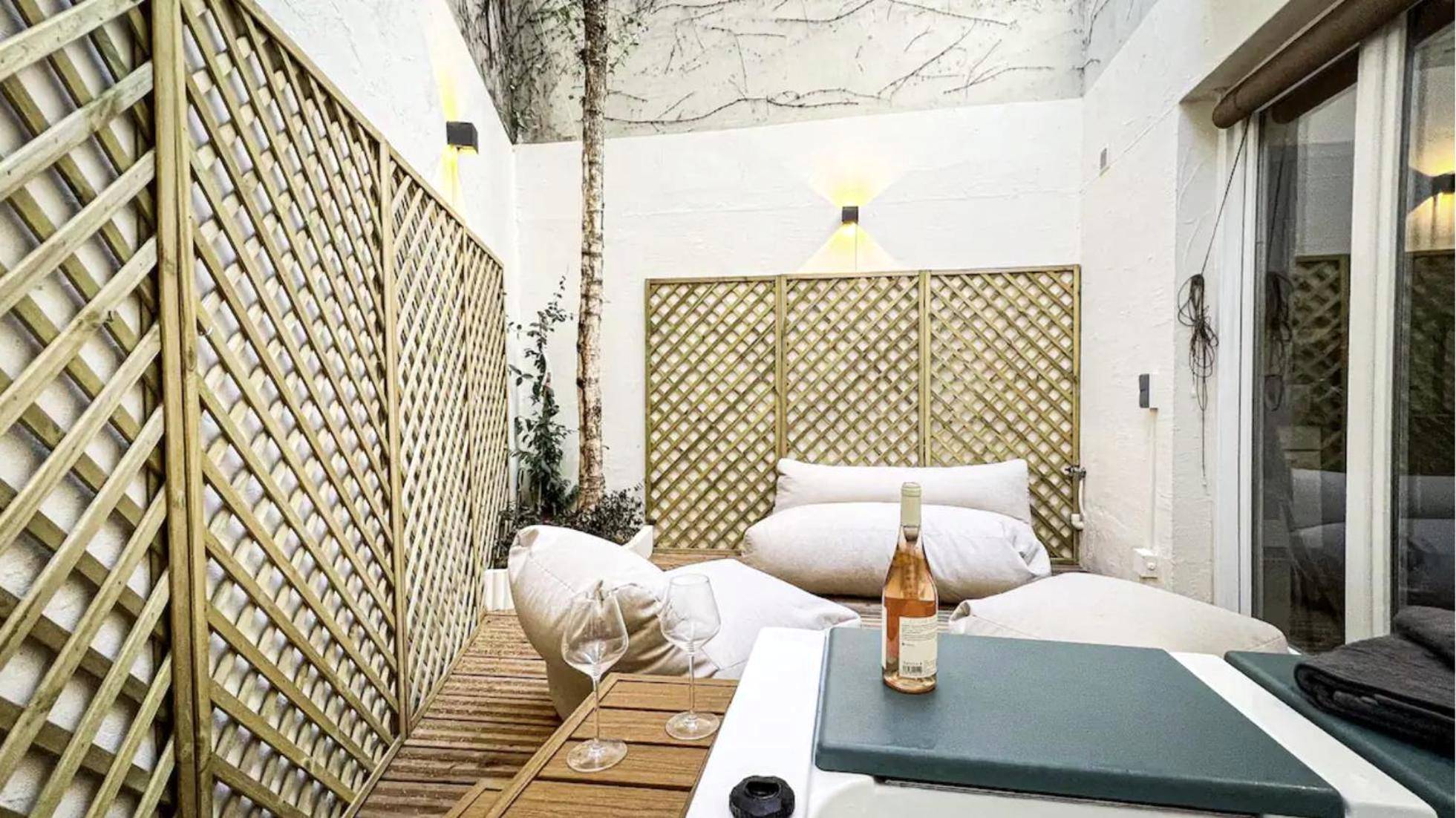 Espace détente avec poufs et bouteille de vin - Suite luxueuse avec jardin privatif et jacuzzi