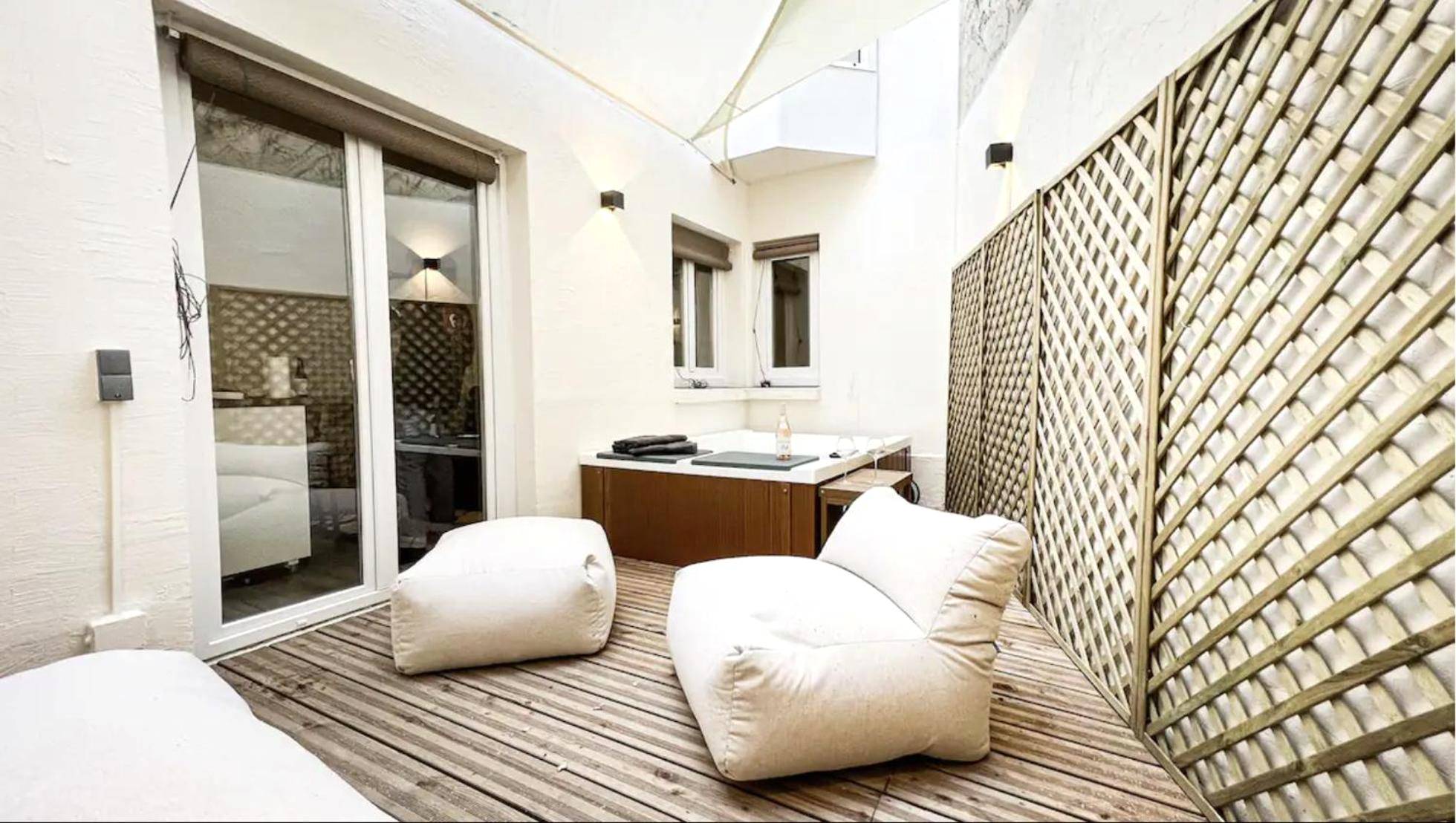 Terrasse privative avec spa et fauteuils blancs - Suite luxueuse avec jardin privatif et jacuzzi