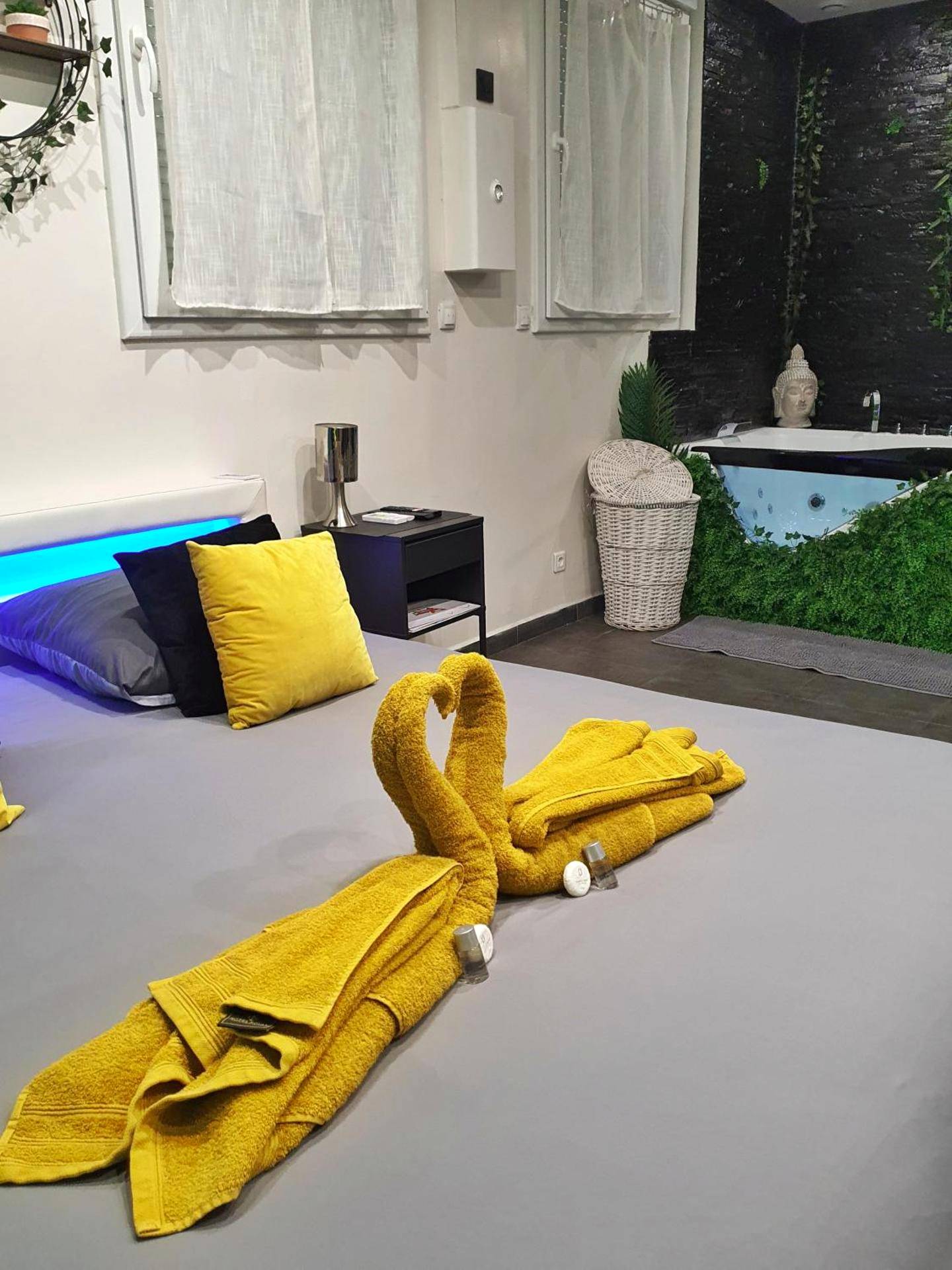 Cygnes en serviettes jaunes sur lit king size - Suite Jacuzzi Privatif Plage Des Catalans