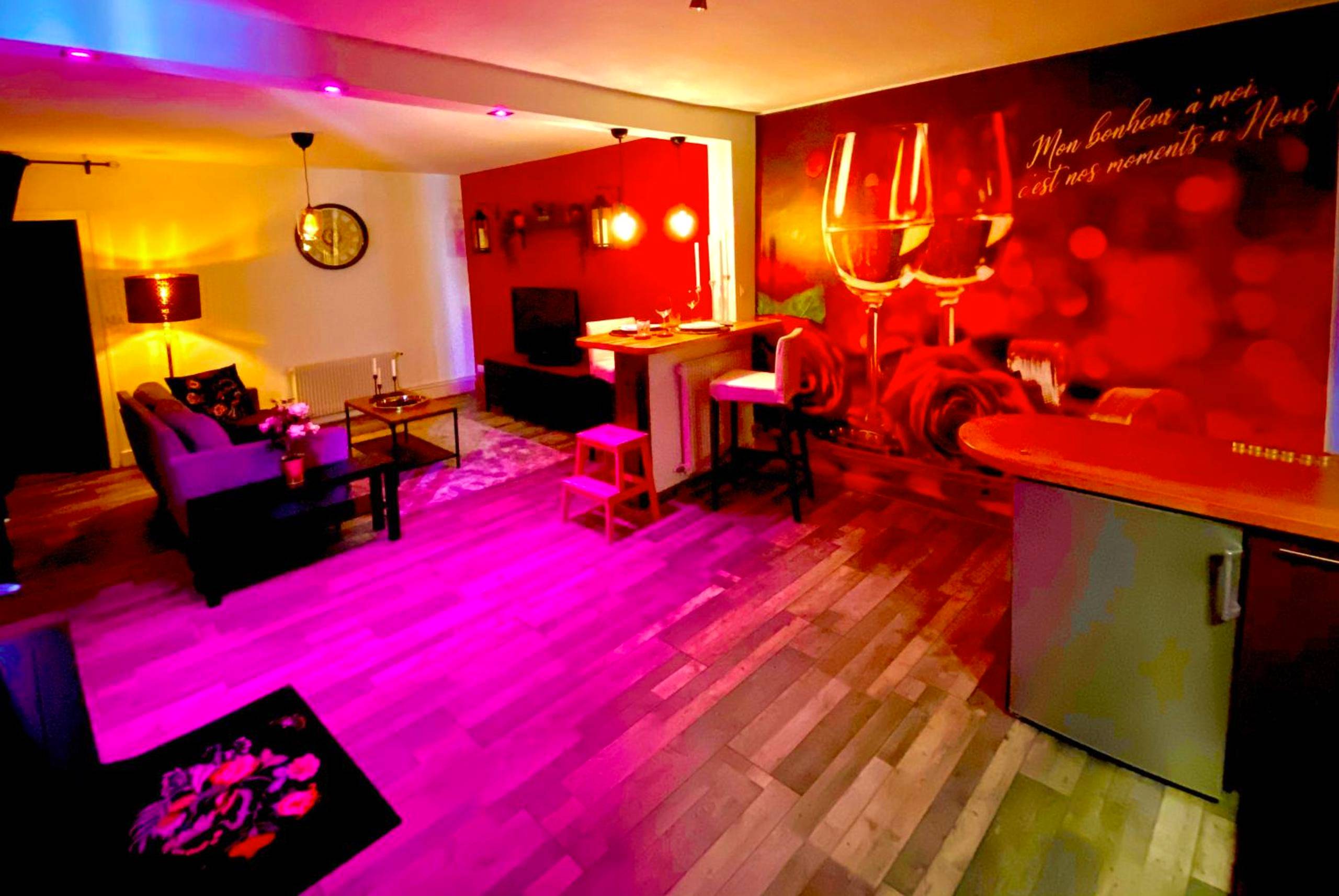 Espace salon et cuisine avec lumière rose - Suite avec Jacuzzi et Sauna Privée