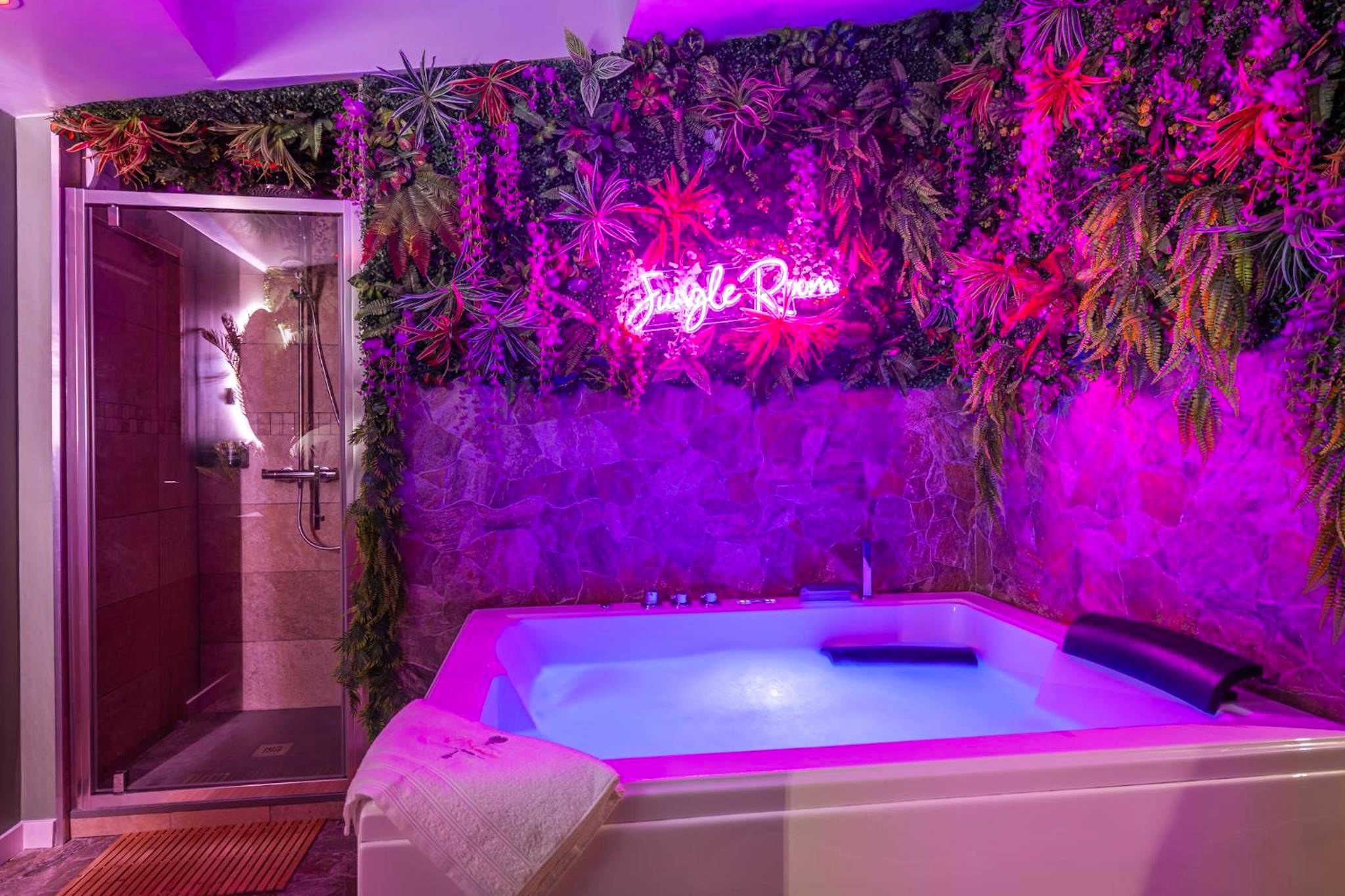 Jacuzzi avec néon rose et mur végétal - Love Room La Flèche - Suite jungle amour détente