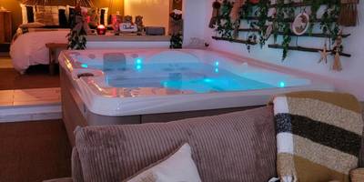 Espace salon avec canapé et jacuzzi éclairé - Suite & SPA Just Dream 28