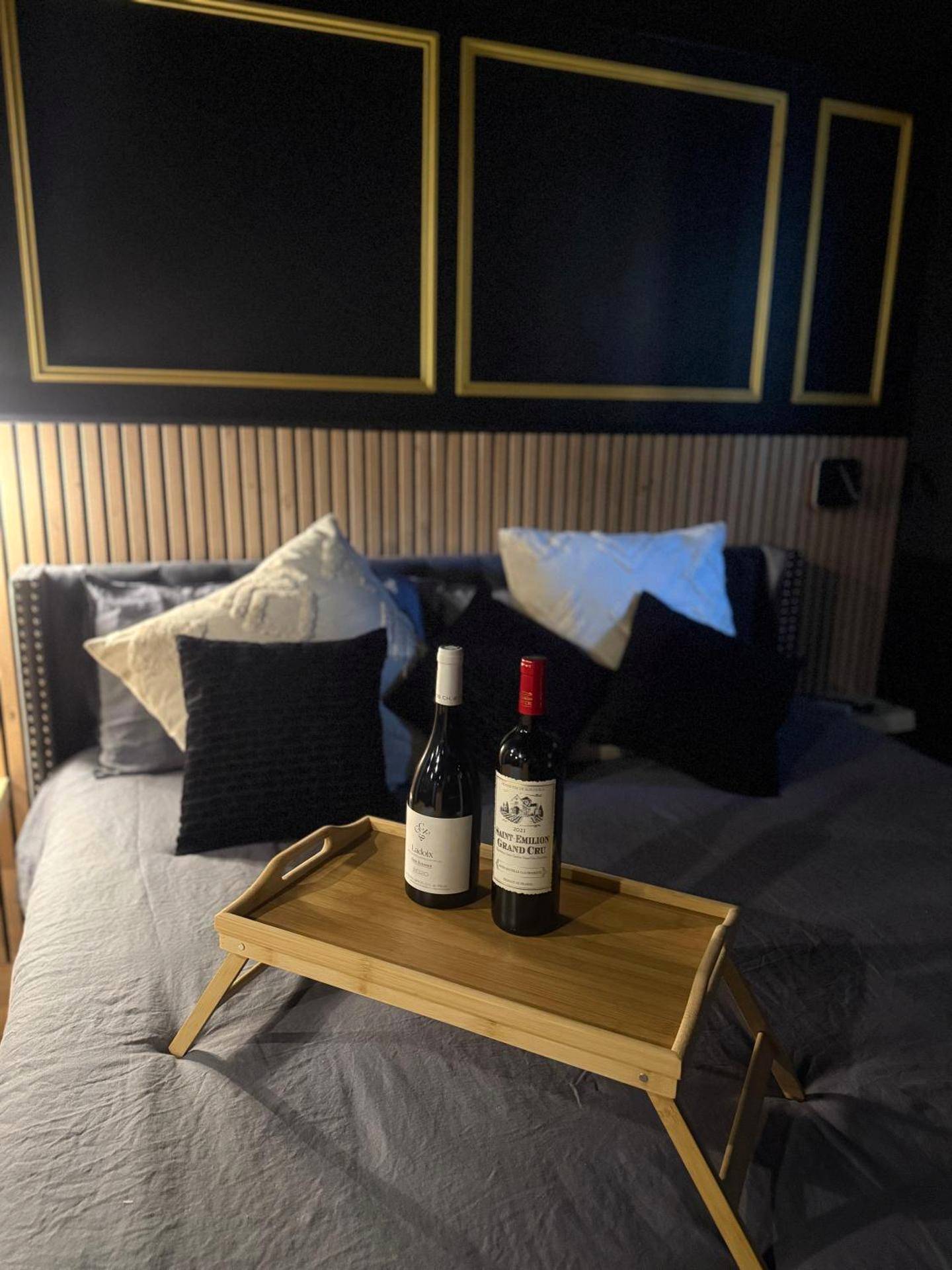 Bouteilles de vin sur plateau au pied du lit - Loveroom La suite des murmures