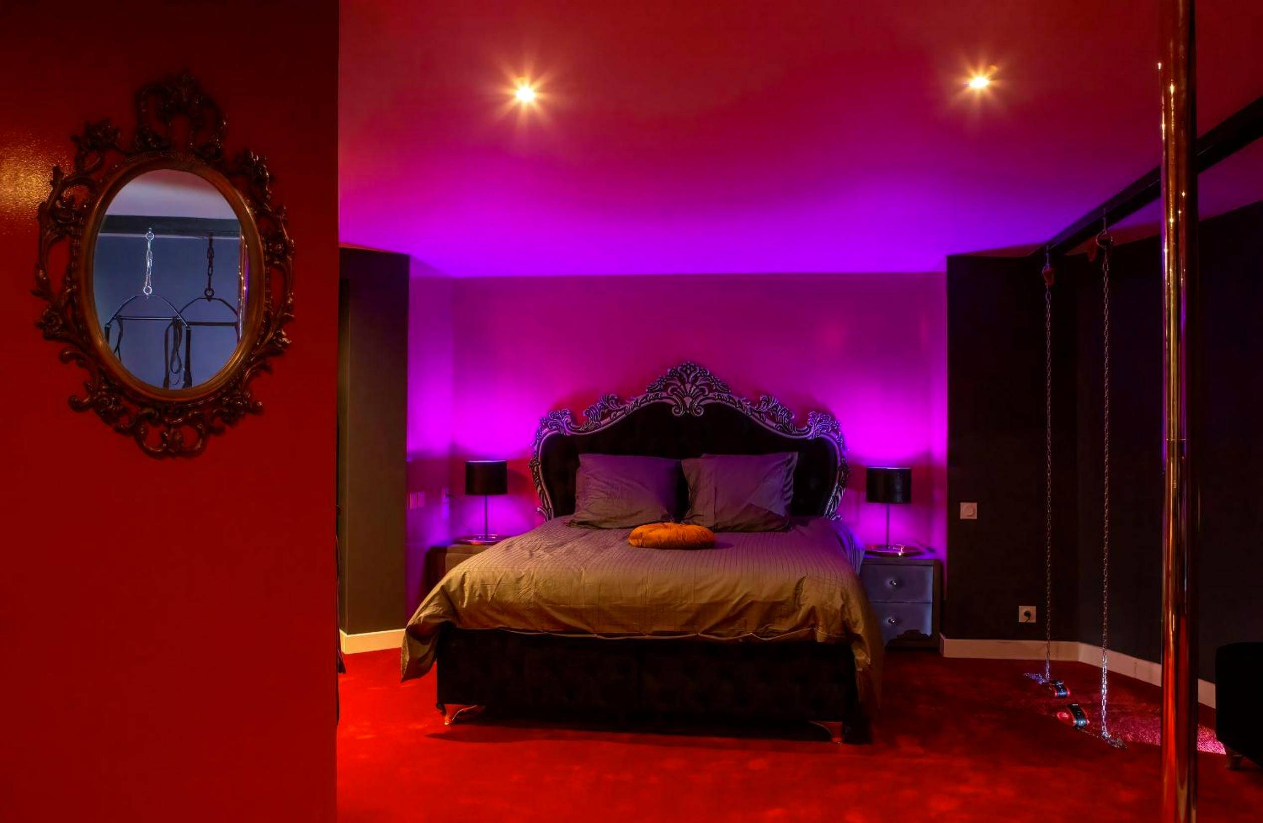 Lit king size sous néons violets et balançoire - SUITE PLAYROOM Love Hotel Toulouse