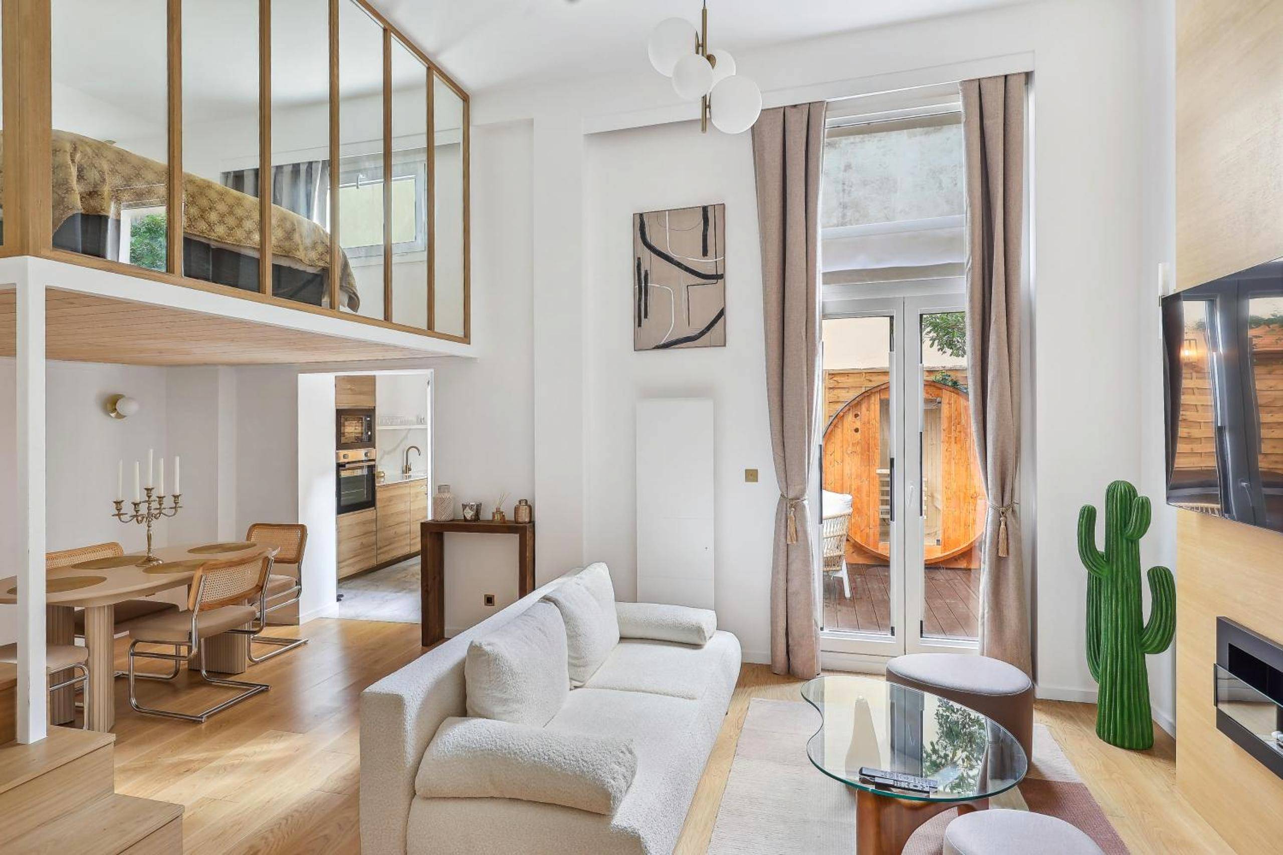 Salon lumineux avec canapé blanc et mezzanine - Love Room Paris - Suite luxueuse avec jardin privé Sauna et Jacuzzi